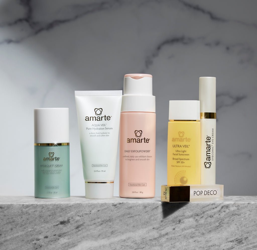 Assorted skincare products from the brand Amarte arranged on a marble surface.