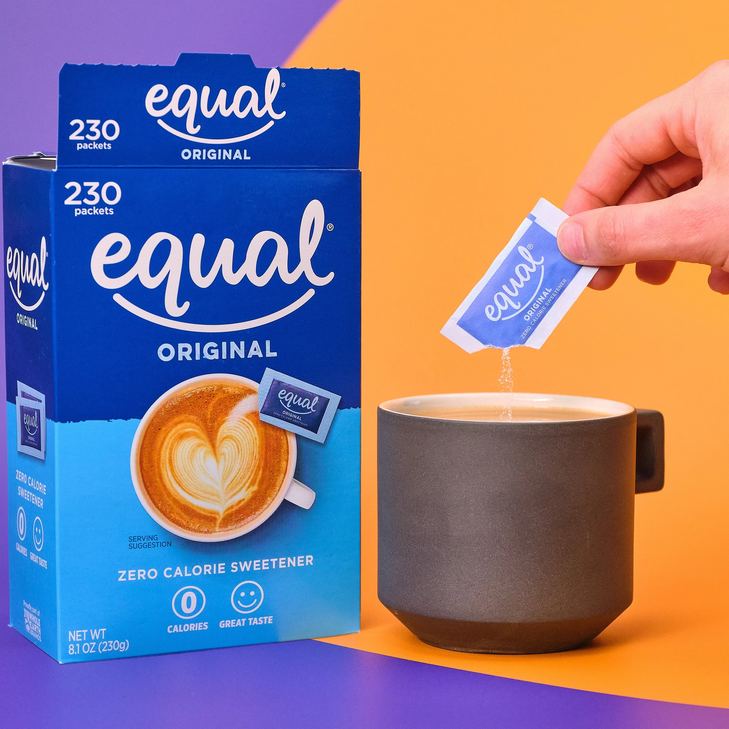 A blue box of Equal original zero calorie sweetener packets and a hand holding a packet over a black mug, with a yellow background and colorful surface.