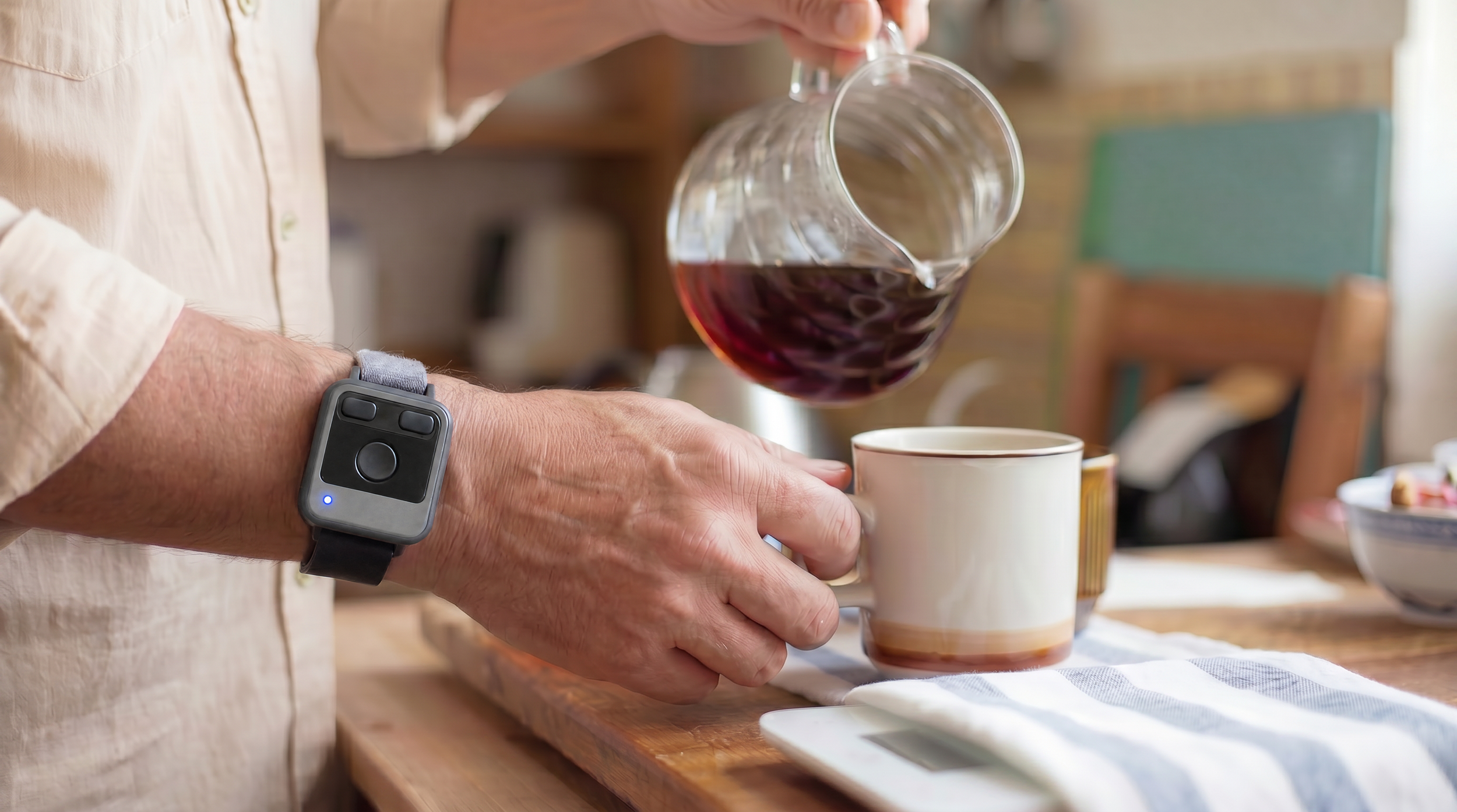 Person pouring red wine from a glass decanter into a white mug in a kitchen.