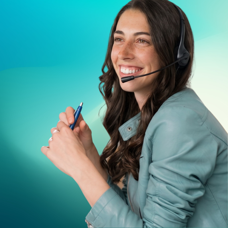 A young woman with long dark hair smiling while wearing a headset and holding a pen against a teal gradient background.
