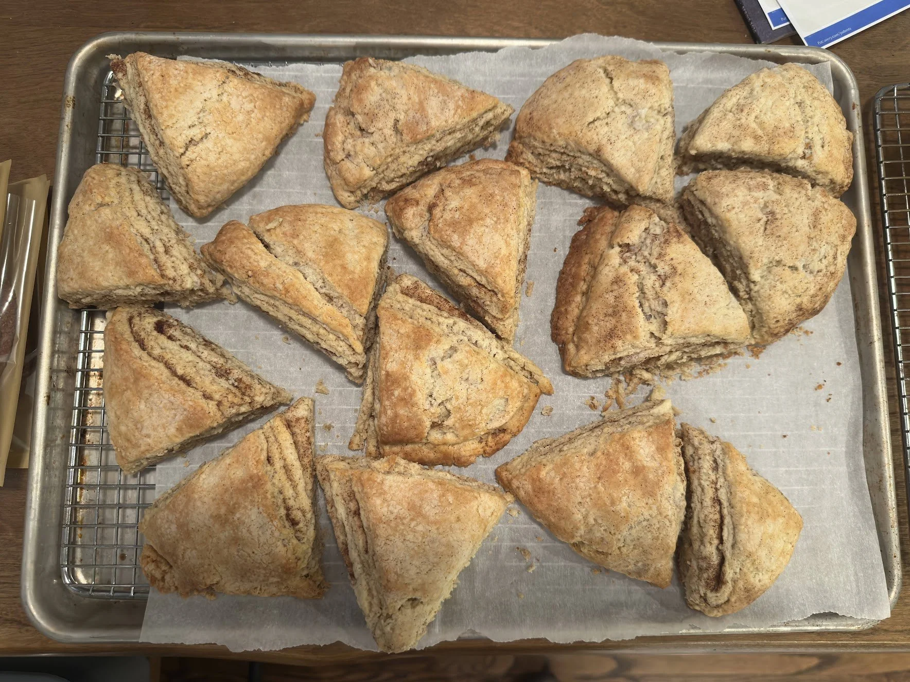 Several slices of cinnamon roll scones on a baking sheet lined with parchment paper, ready to be baked or served.