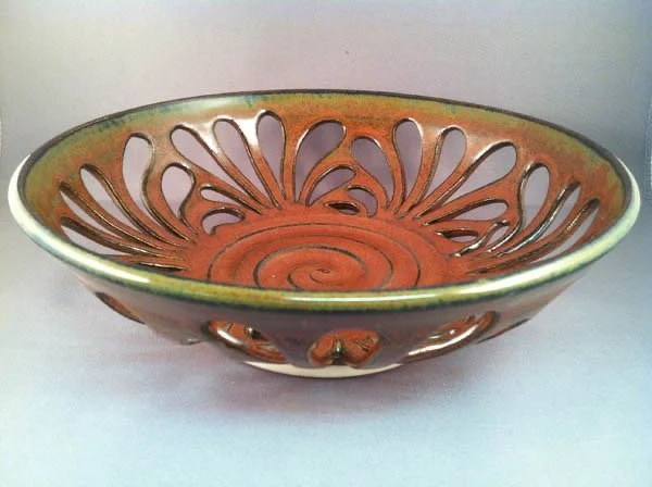 Decorative ceramic bowl with openwork design and spiral pattern inside.