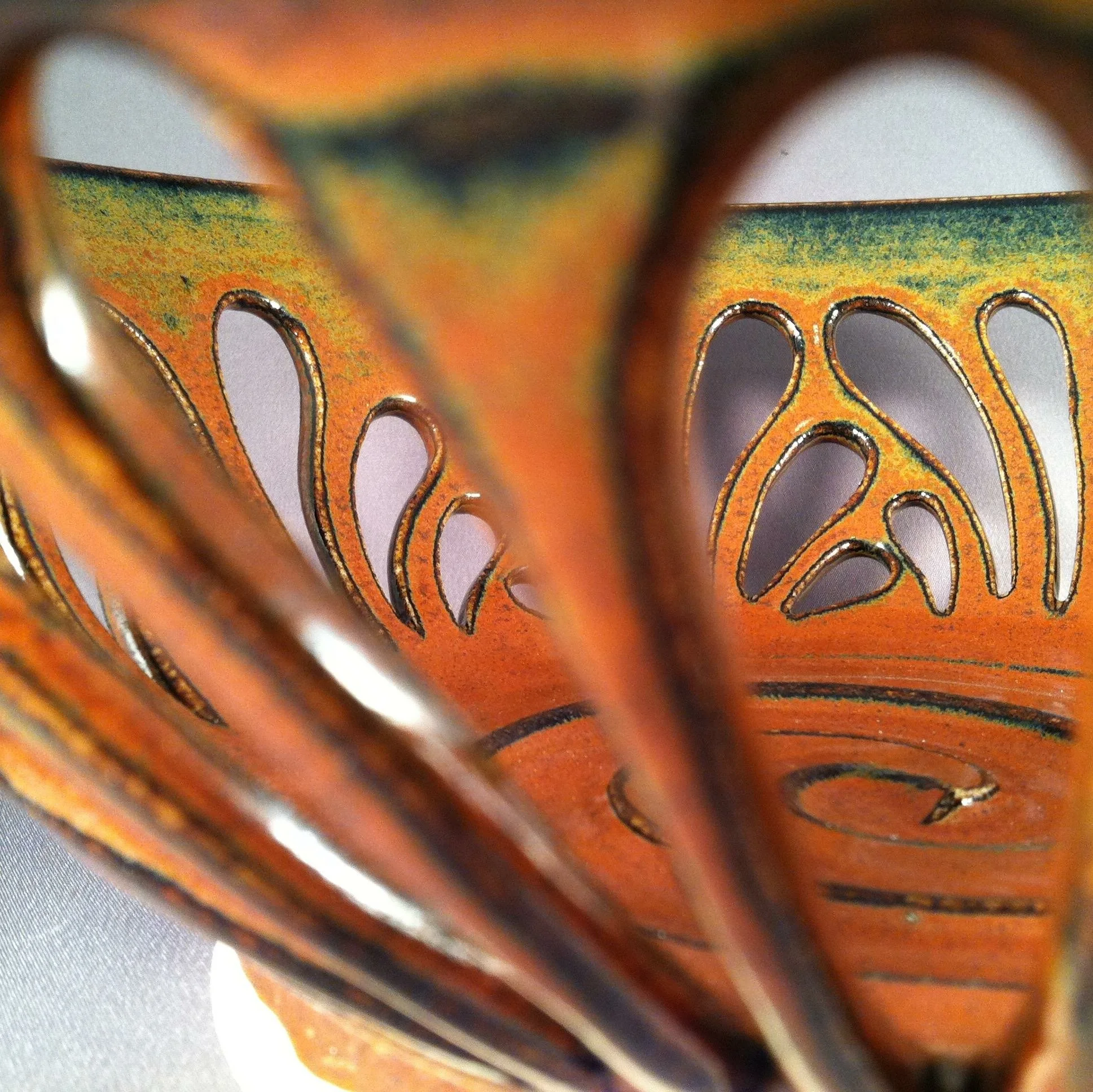 Close-up of an orange decorative item with circular openings and colorful patterns, possibly made of metal or ceramic.