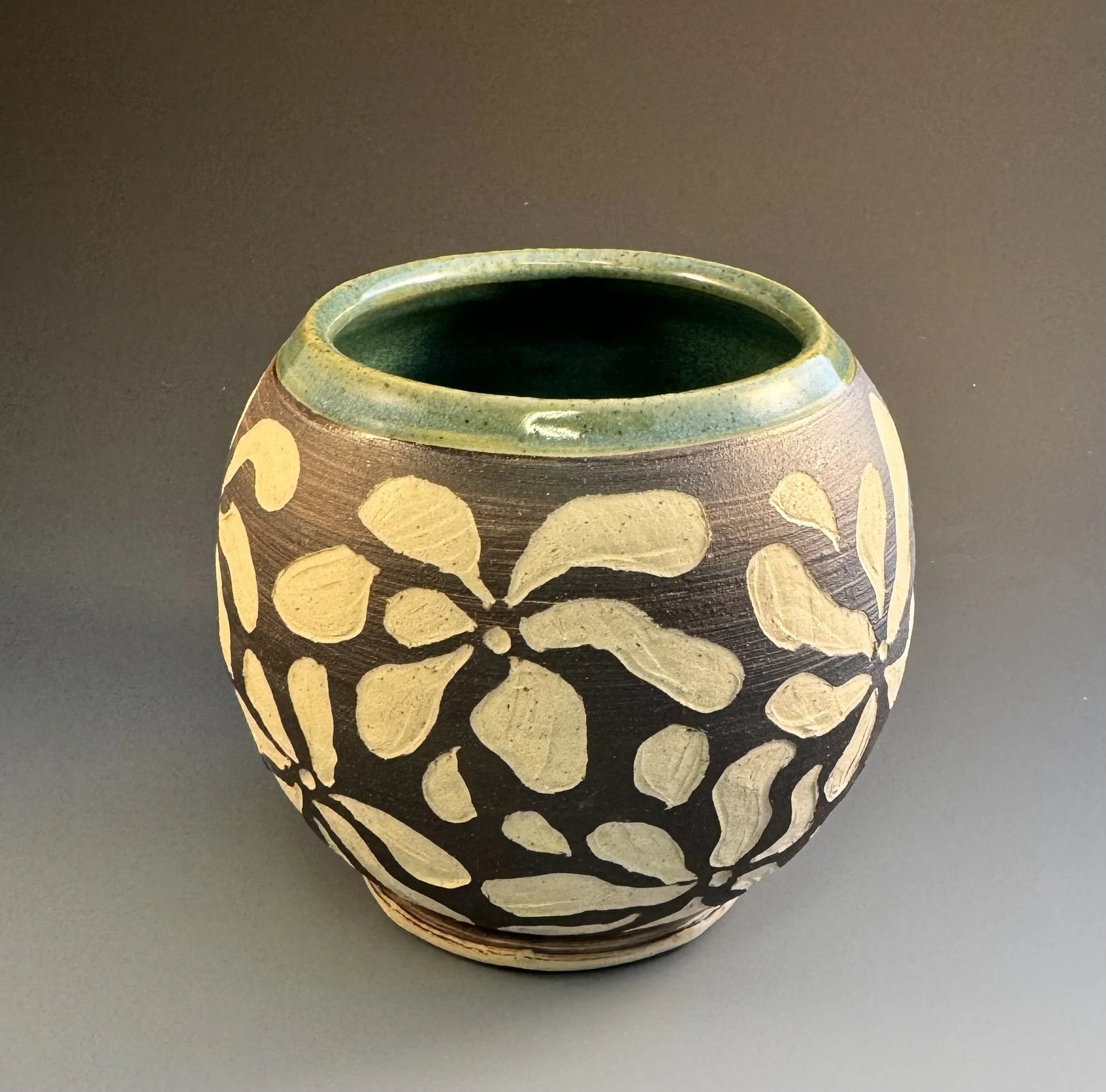 Close-up of a decorative ceramic vase with yellow and black designs, set against a dark background.