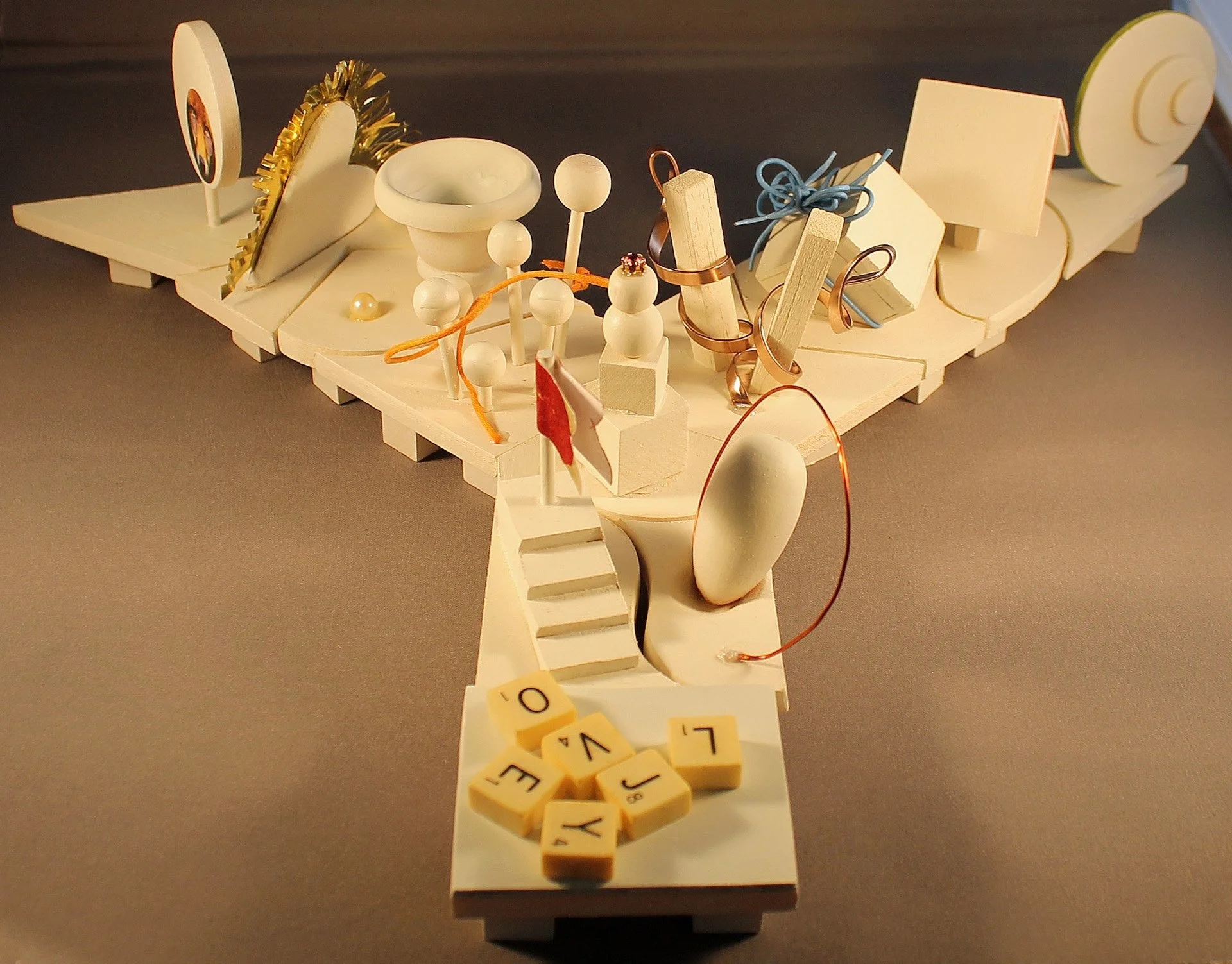 A miniature model of Noah's Ark featuring small figurines, animal figures, and game pieces, displayed on a platform.