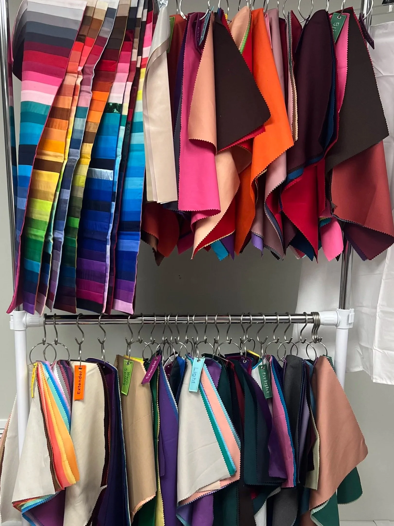 Color samples and fabric swatches hanging on a display rack, organized by color and type.