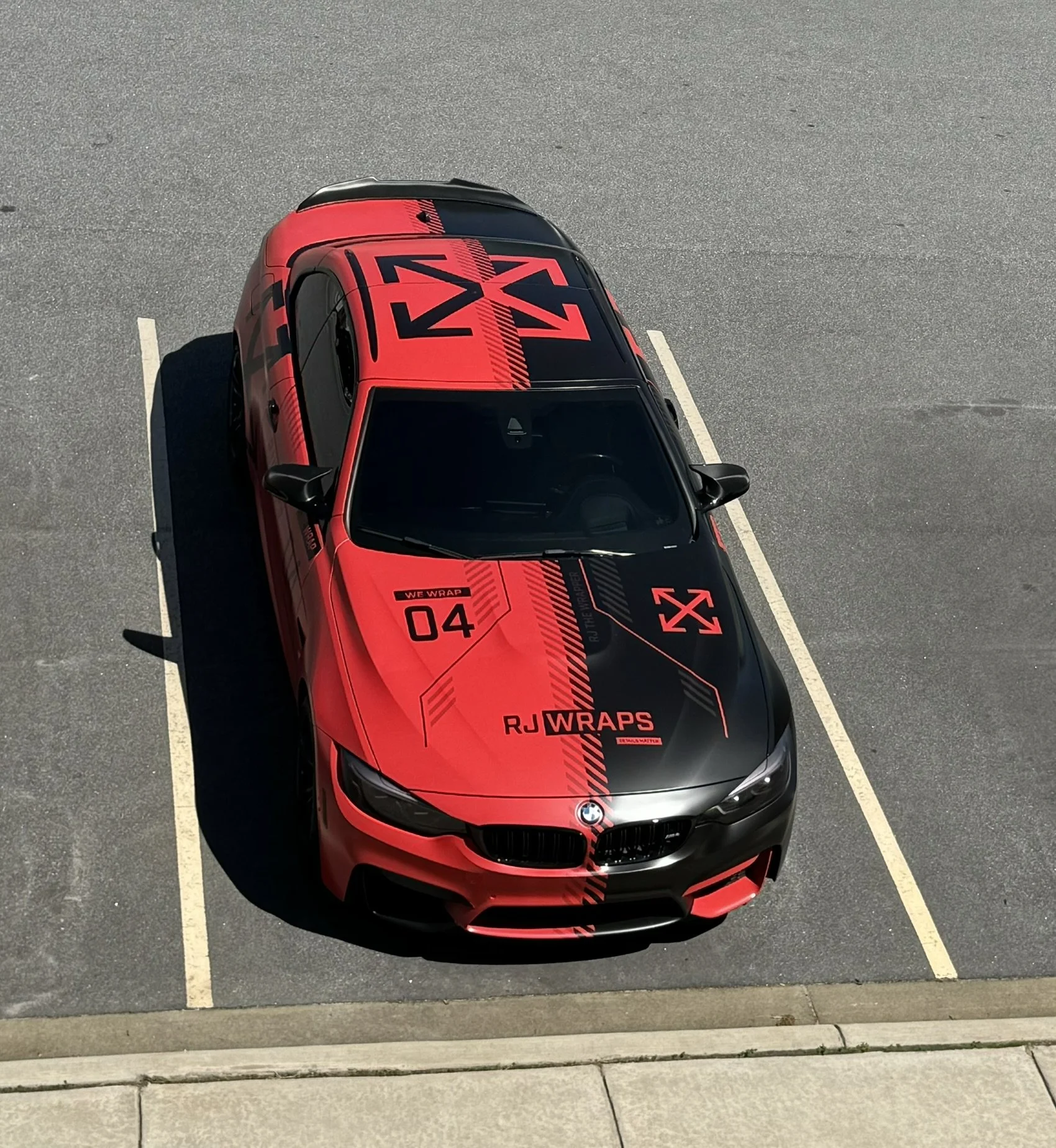 Top-down view of a red BMW car with black decals parked in a parking lot.