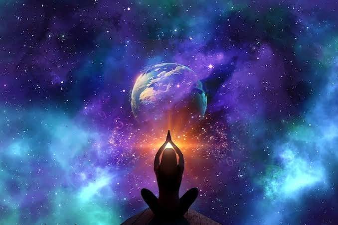 Silhouette of a person practicing yoga in a seated meditation pose with hands in prayer position, facing outer space with Earth and colorful nebulae in the background.