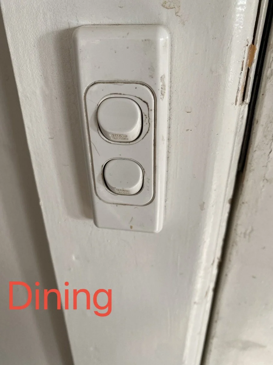 A close-up of a white light switch with two buttons on a white wall, showing some dirt and wear. The word "Dining" is written in red text in the bottom left corner.