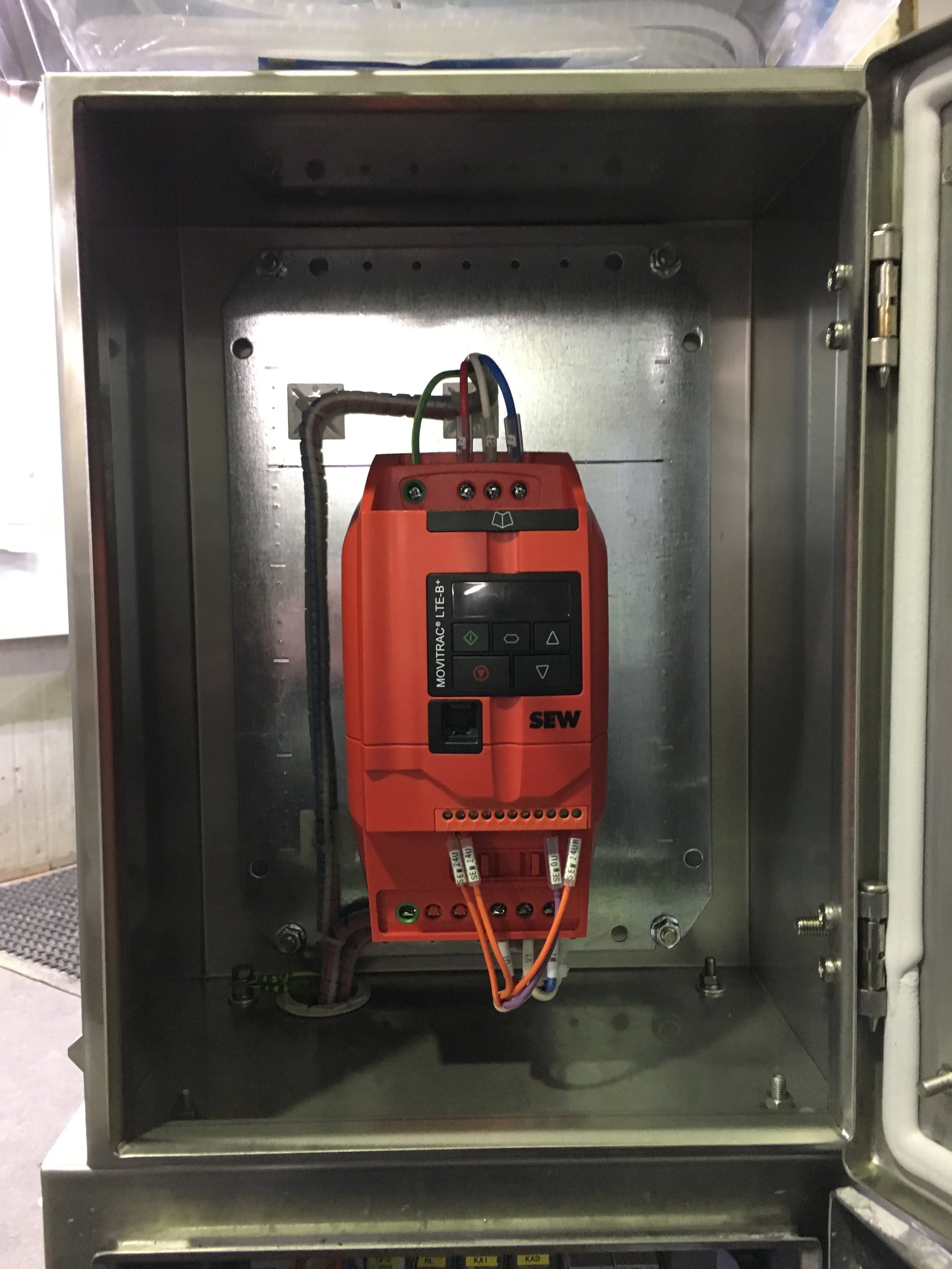 Inside an electrical control panel with wiring and a red testing device attached.