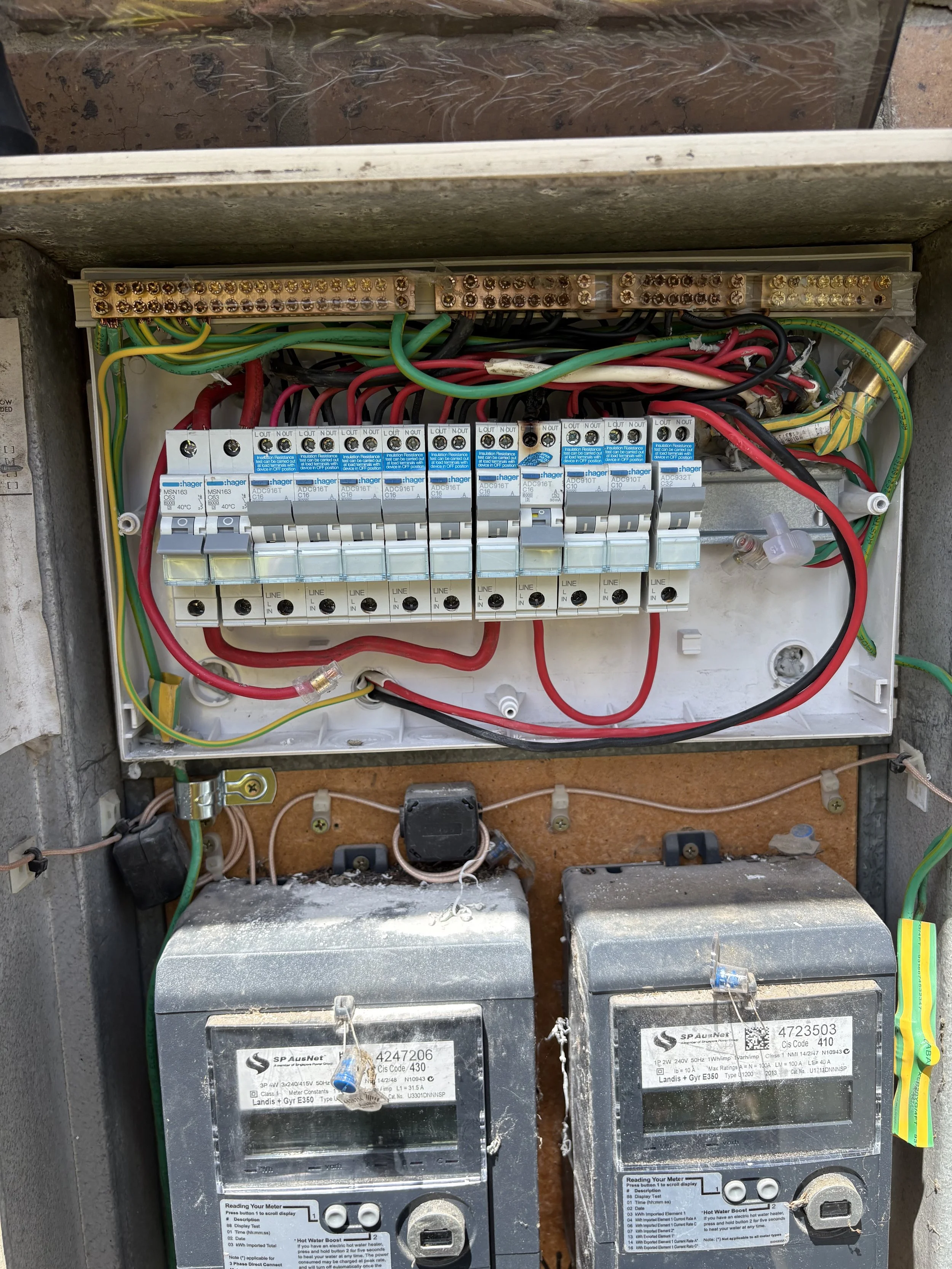 Electrical circuit box containing circuit breakers, wiring, and two large batteries labeled 'SP AusNet'.