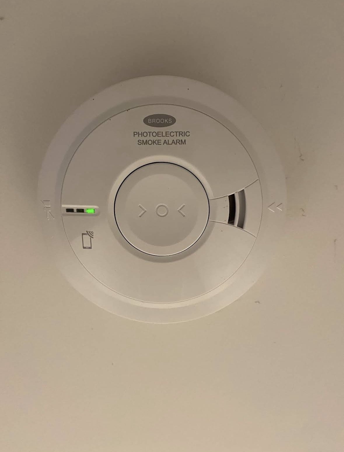 Ceiling smoke alarm with controls, indicator lights, and a small vent.