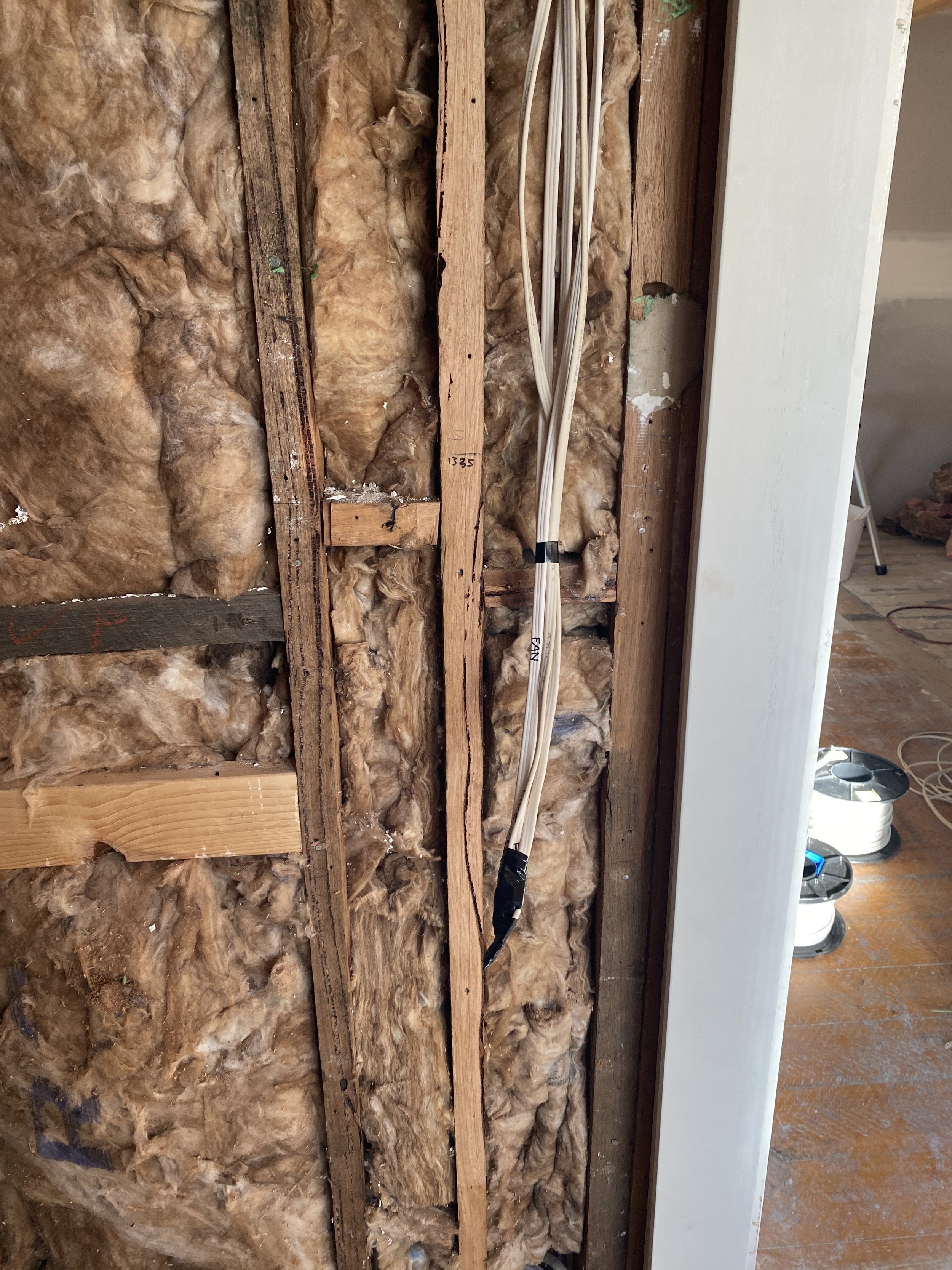 Insulation and electrical wiring in a wall cavity during home renovation.