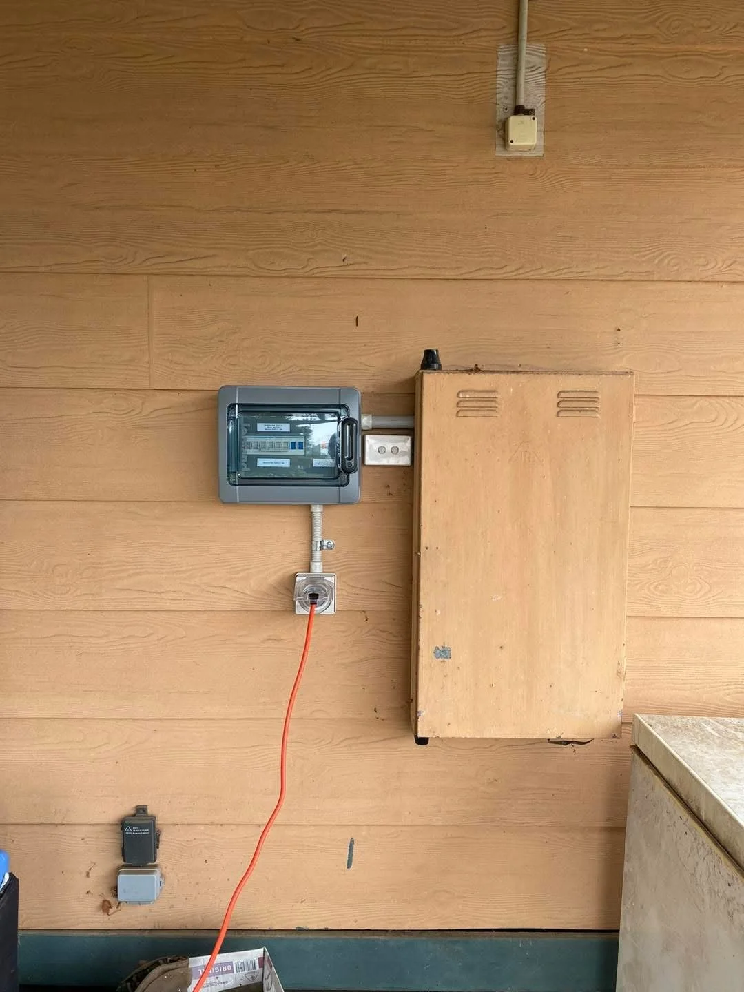 Electrical meter, electrical box, and outlets on a wooden wall.