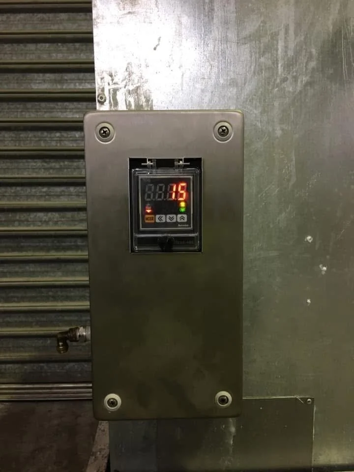 A metallic industrial control panel with a digital display showing a red number 35, mounted on a stainless steel surface.