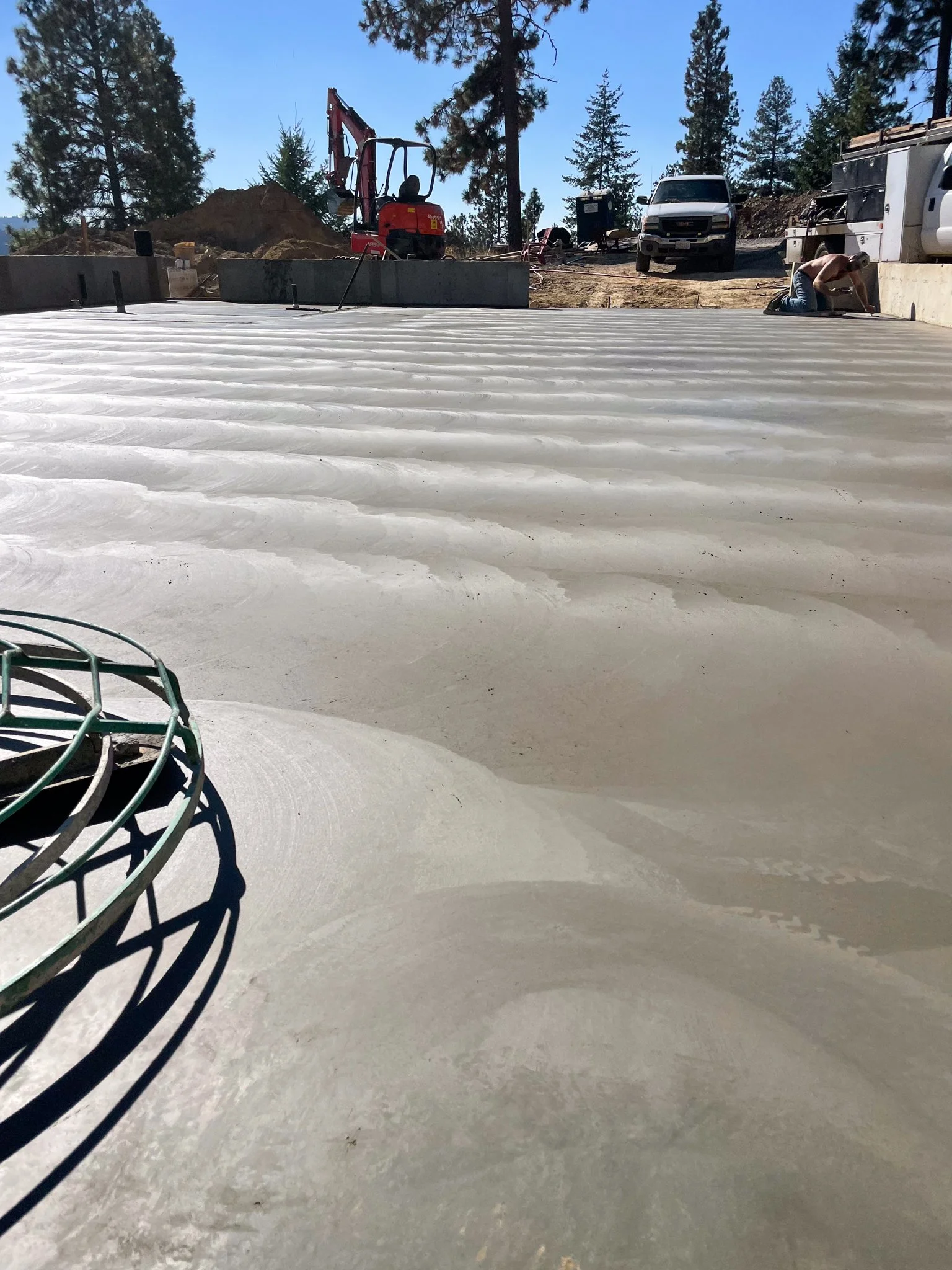Pouring white concrete on a construction site with construction tools, vehicles, and a worker.