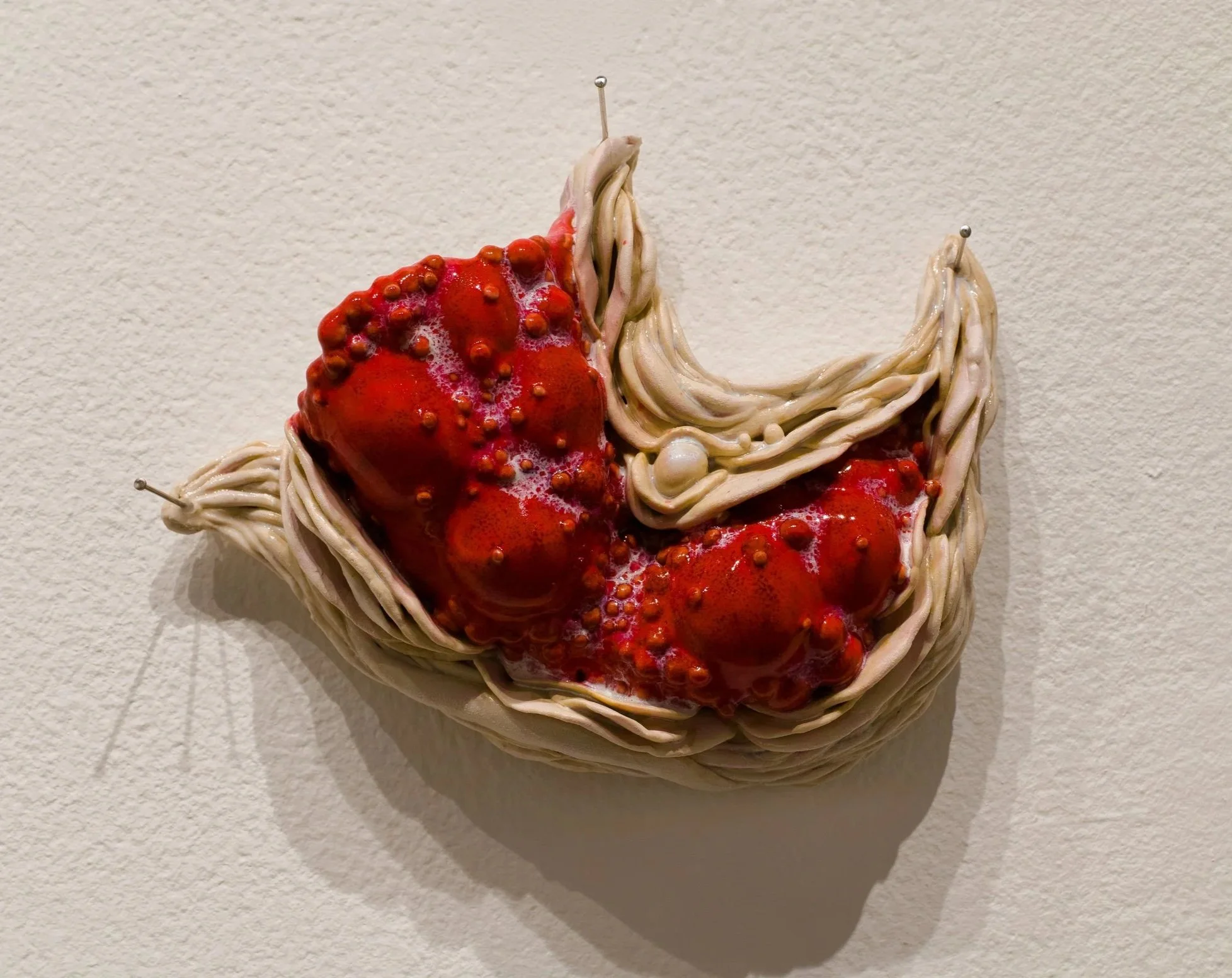 Ceramic wall sculpture of abstracted bumpy diseased flesh.