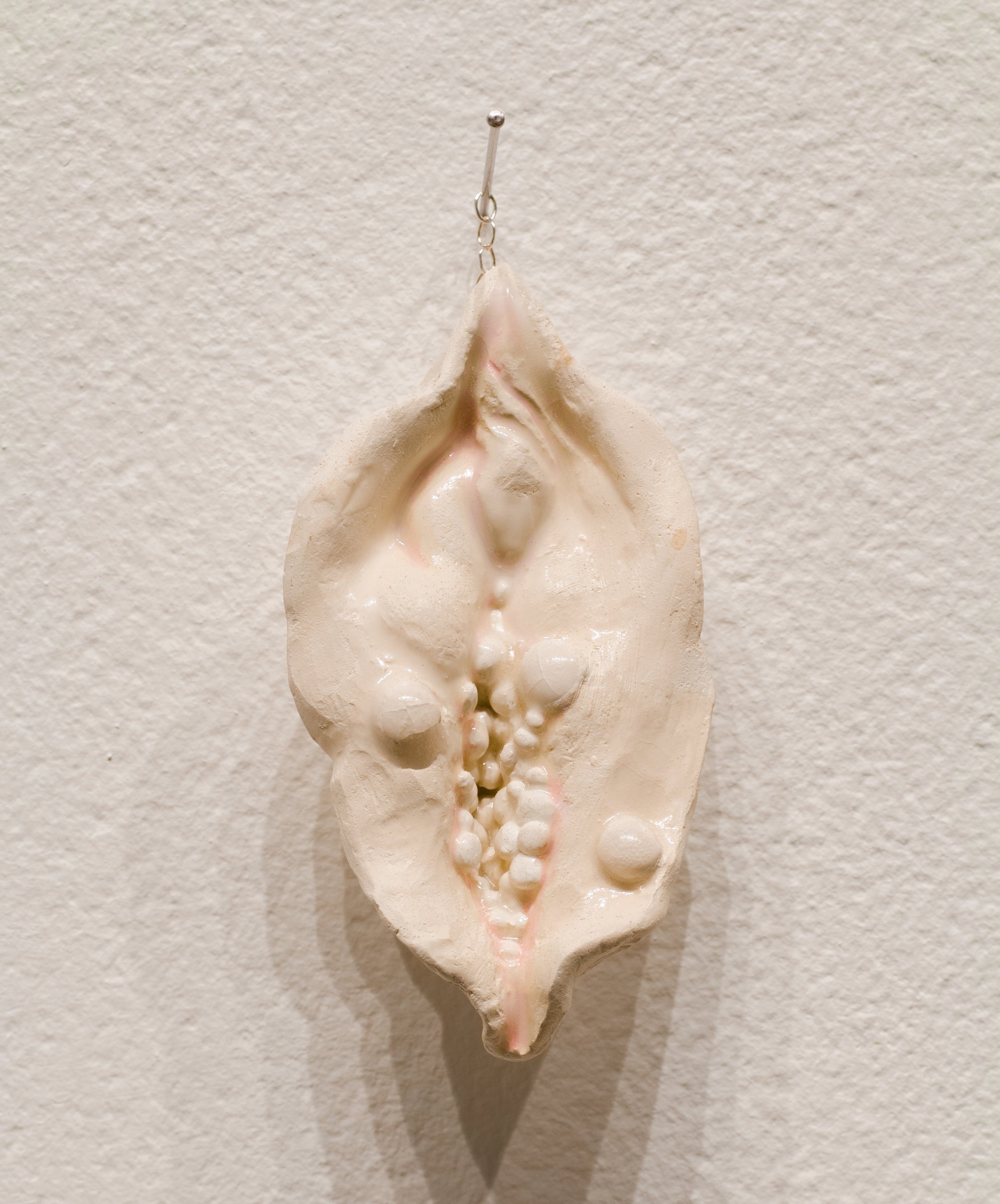 Ceramic wall sculpture of cream and pink abstracted bumpy diseased flesh.