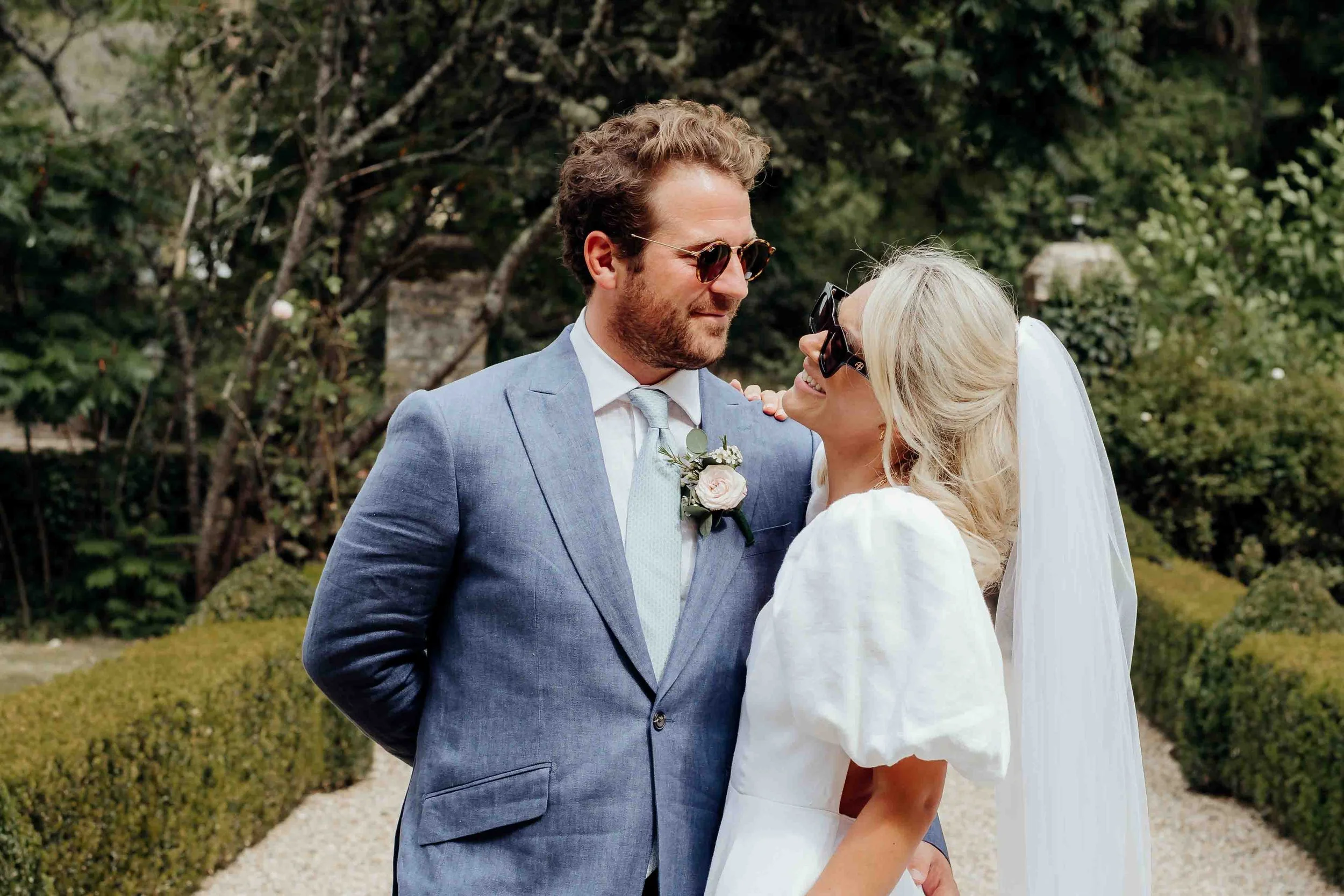 Millie & Toby looking at each other at their wedding with stylish sunglasses on.