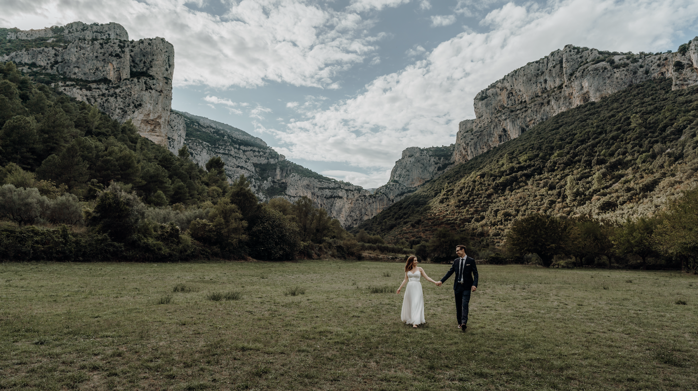 Tabitha and Greg walking in a valley surrounded by mountains in France.