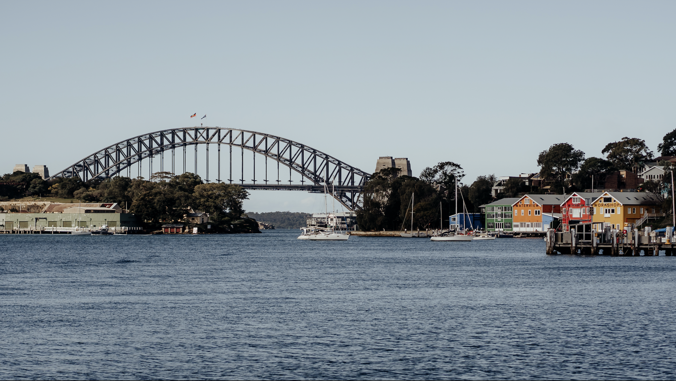 Looking at the Sydney Harbour Bridge with colourful homes to the right of the bridge.