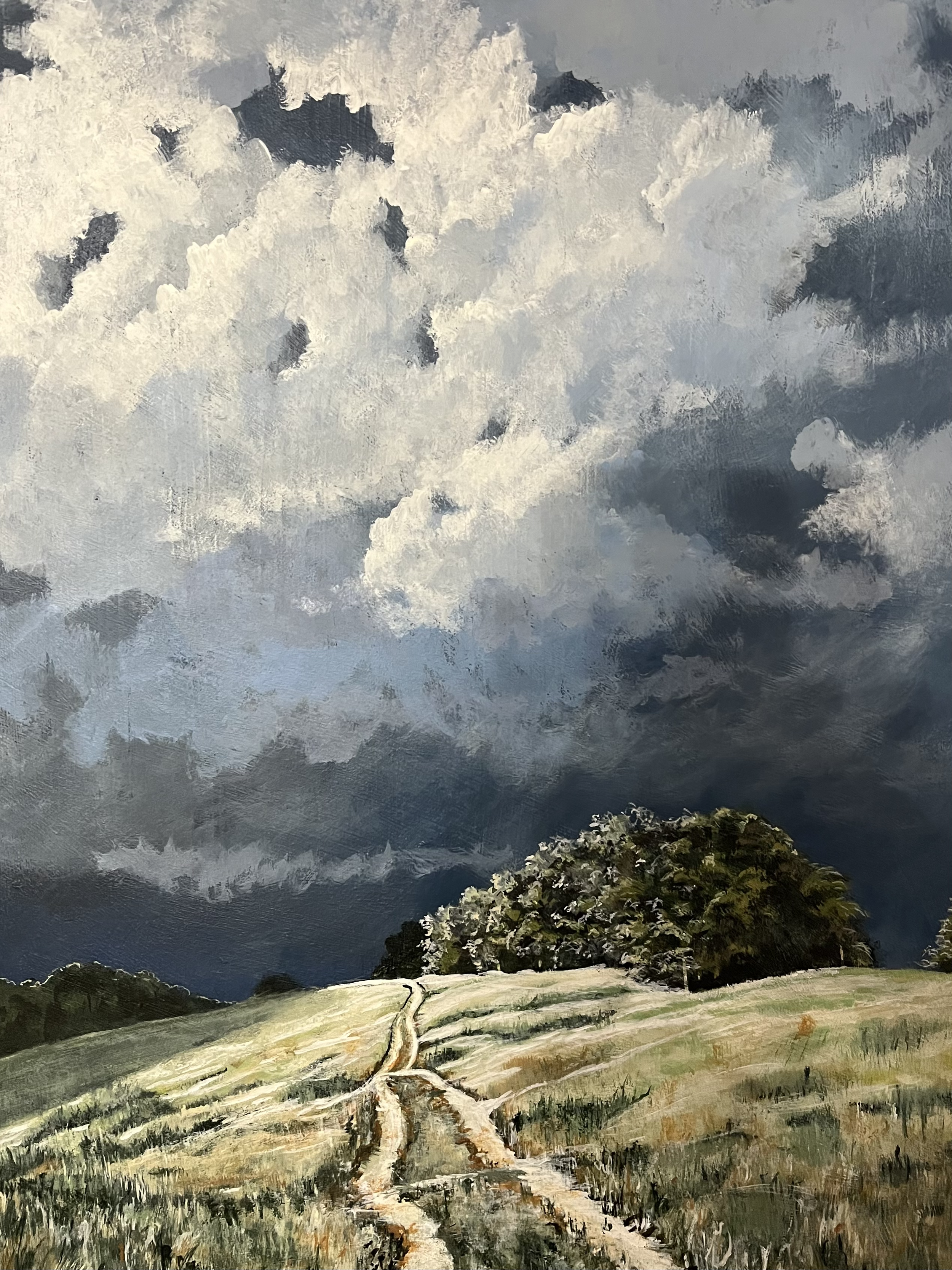 A landscape painting depicting a cloudy sky over rolling hills with a group of trees in the foreground.