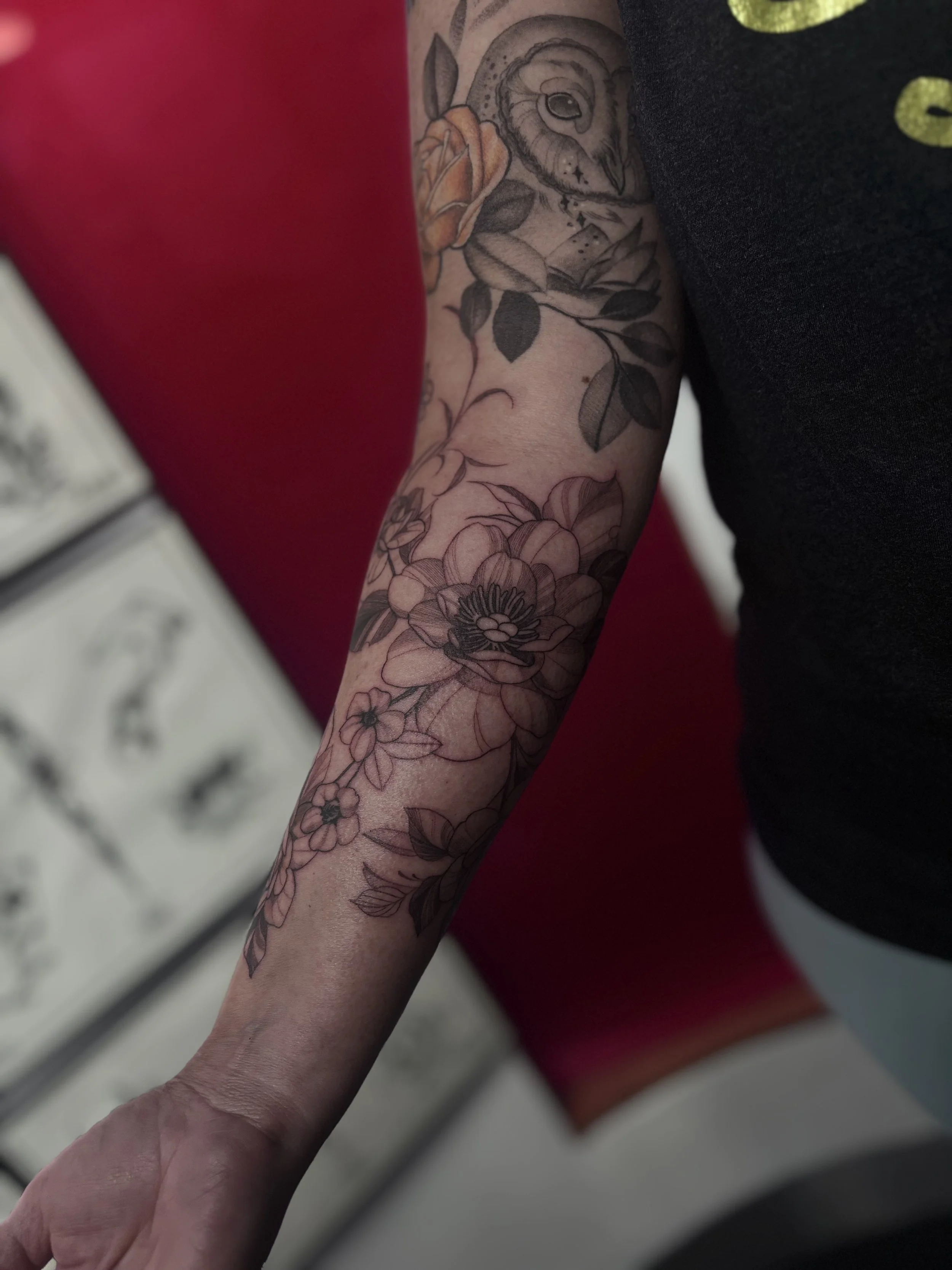 Black and gray illustrative floral tattoo on forearm