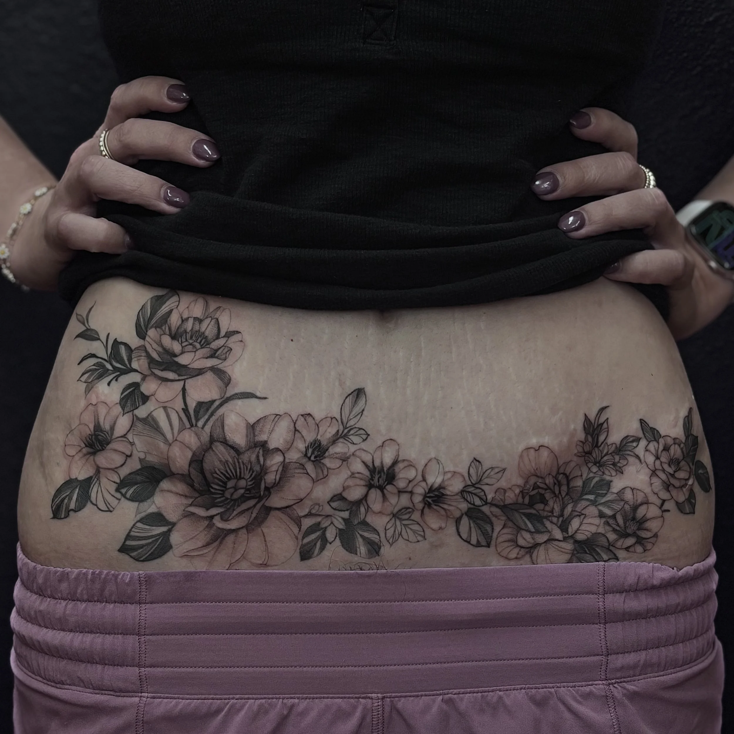Black and gray floral lower back tattoo