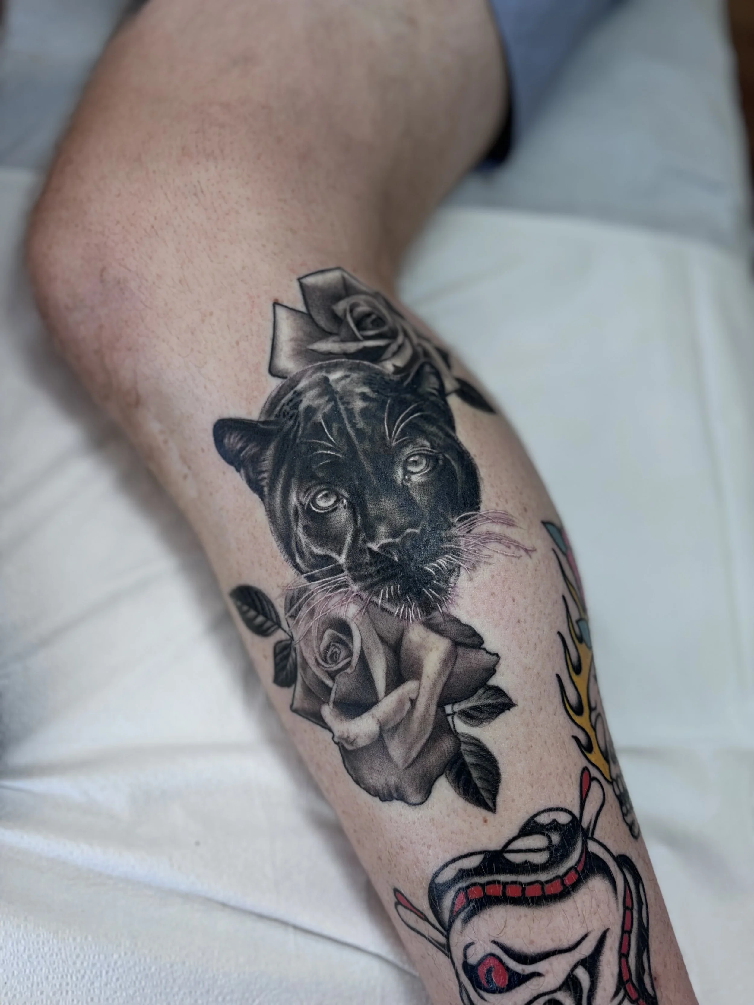 Black and gray illustrative tattoo with flowers on lower leg