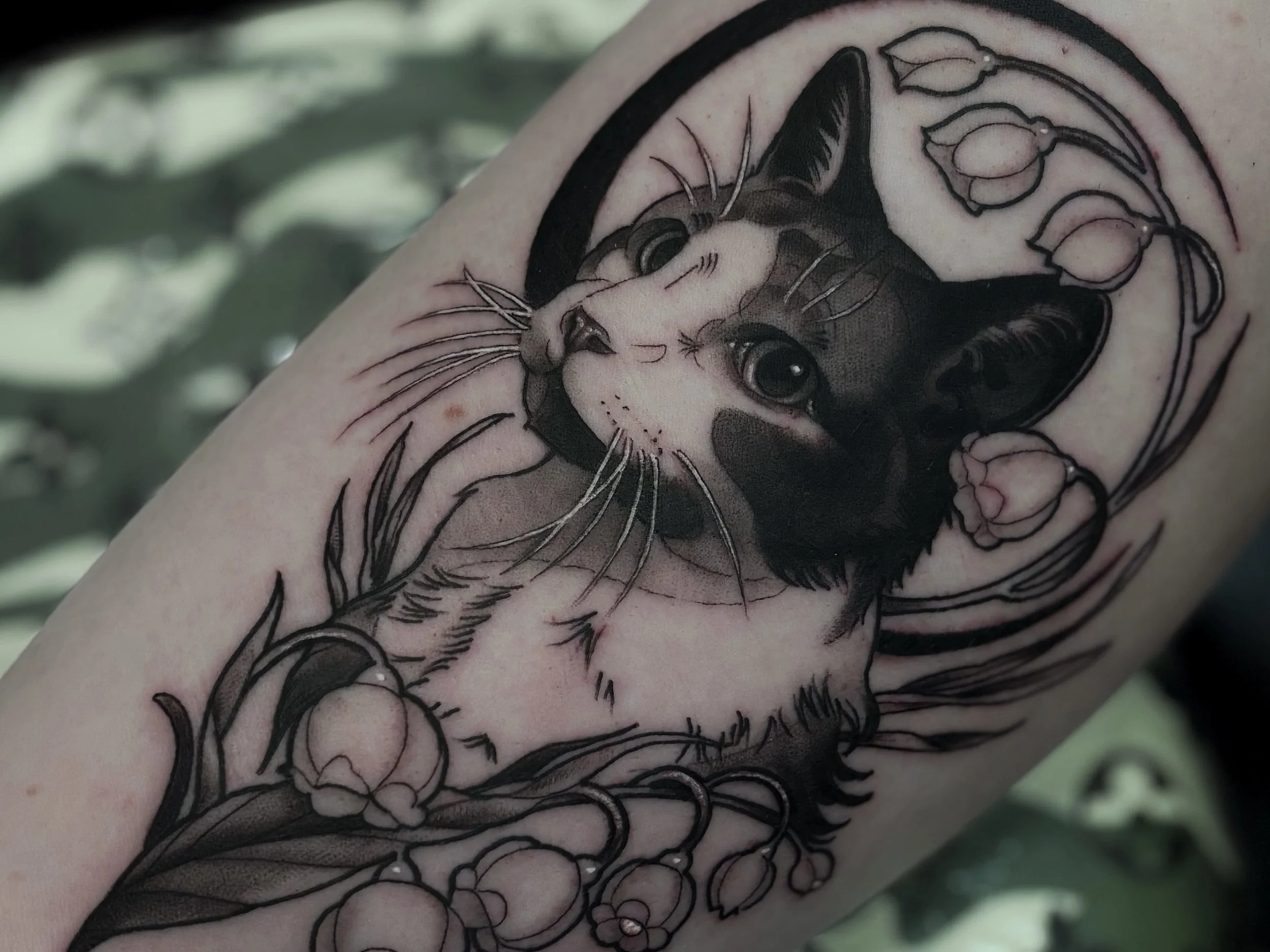 Black and gray cat portrait tattoo with floral details