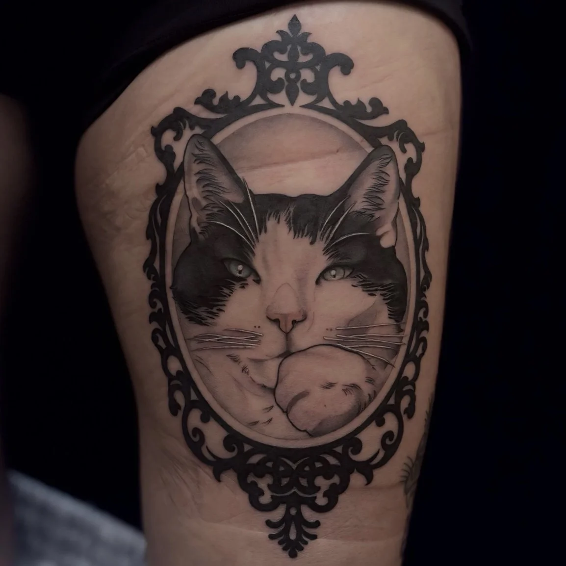 Black and gray cat portrait tattoo on thigh
