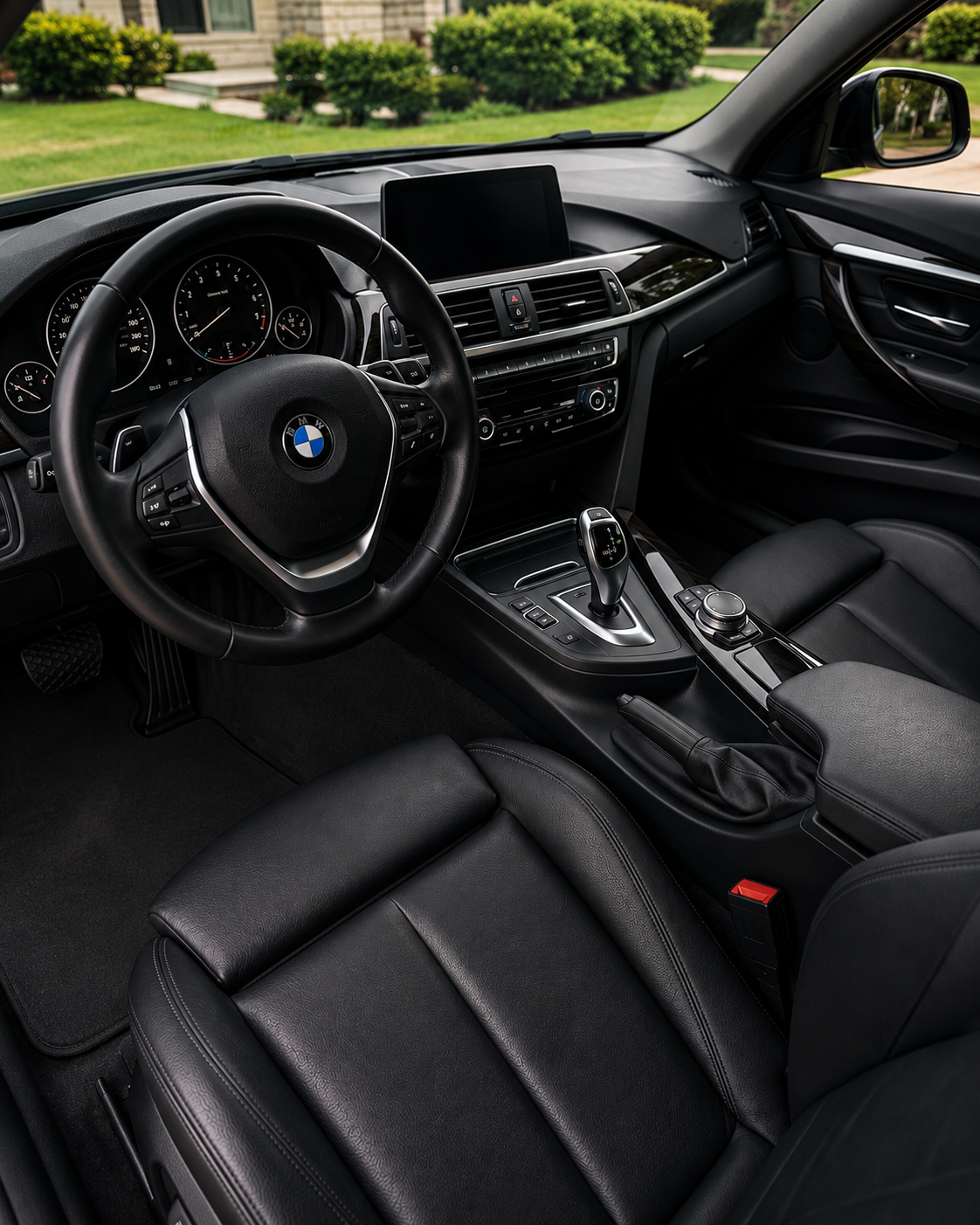 Interior view of a BMW car showing the steering wheel, dashboard, gear shifter, and black leather seats.