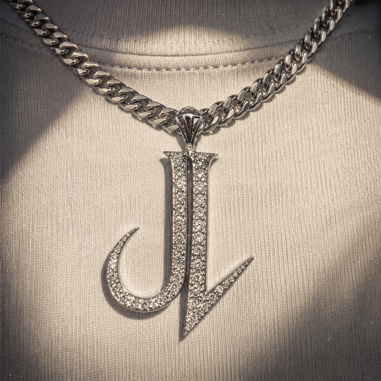 Close-up of a person wearing a silver chain necklace with a large pendant featuring the letters 'J' and 'L' encrusted with small gemstones.
