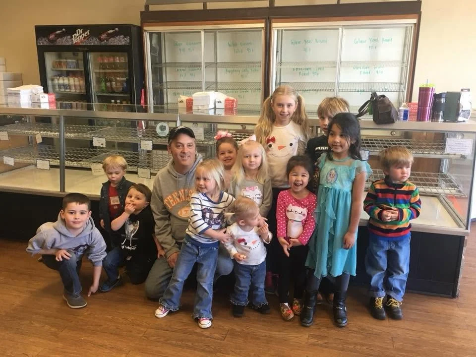 A group of children and an adult posing inside a bakery after a tour.