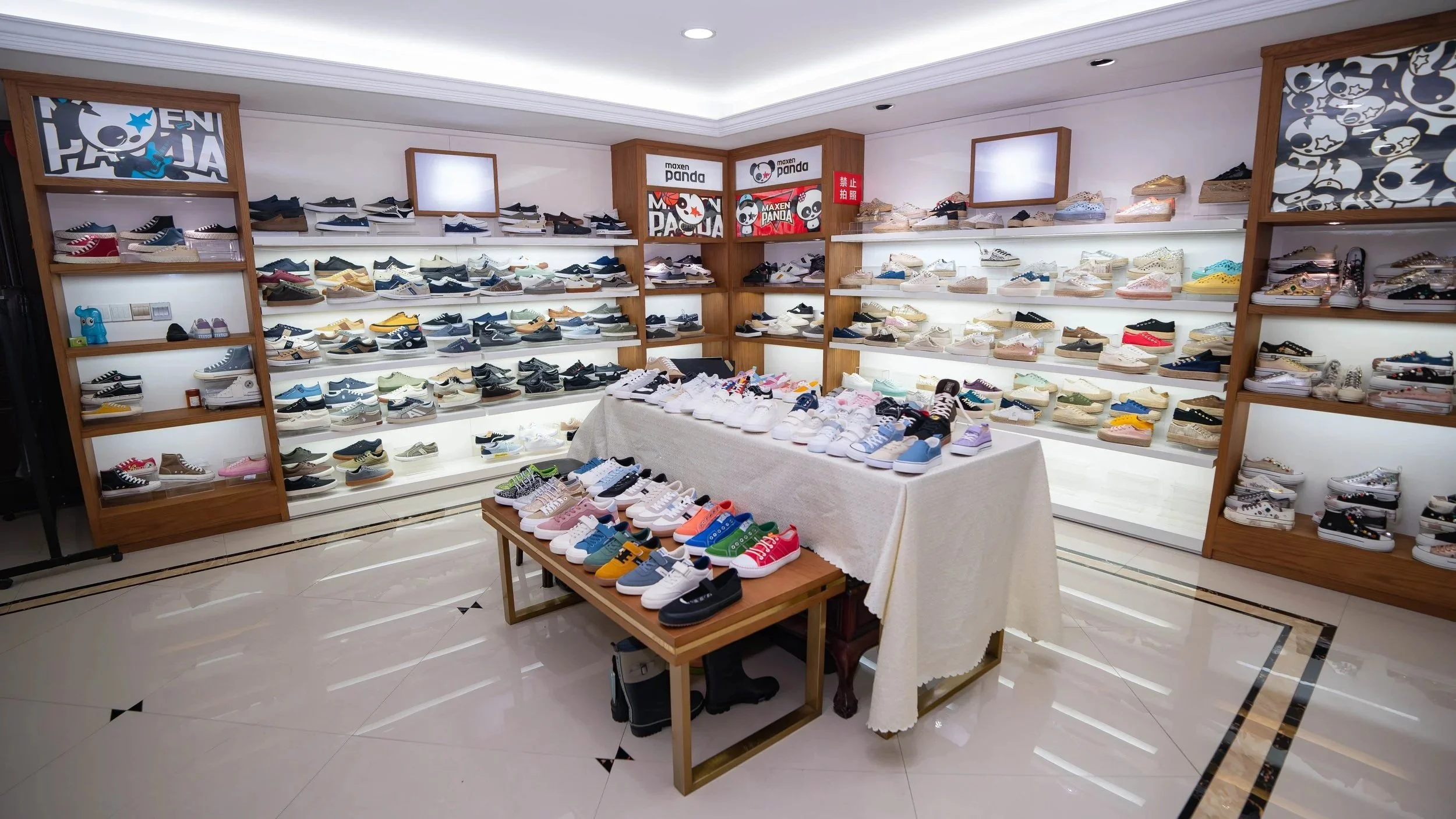 Store display of various sneakers arranged on shelves and tables in a well-lit retail shop.