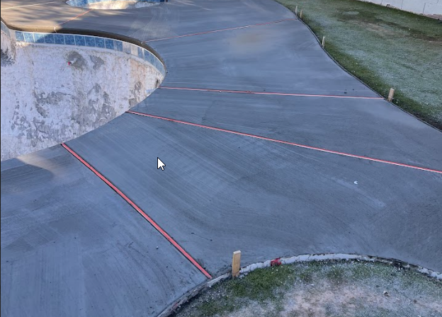 Newly poured concrete pool deck with red string lines for smoothing and shaping during construction.