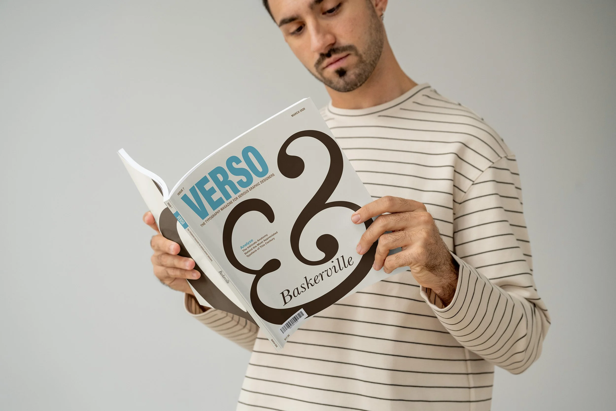 A man wearing a striped shirt is looking at and holding a magazine titled "VERSO" in a teal blue color while the rest of the design has a large dark brown ampersand on the cover.