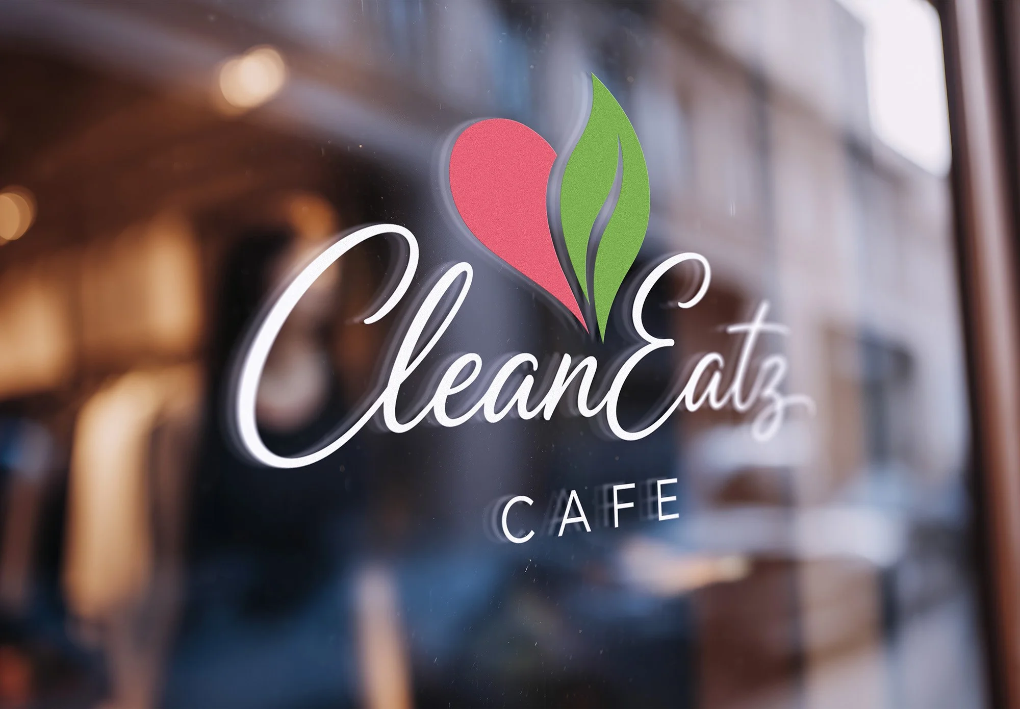 Close-up of a glass window with a logo of a red heart and a green leaf, and the words "CleanEatz"  written in white script while a smaller upper cased "CAFE" is below it.