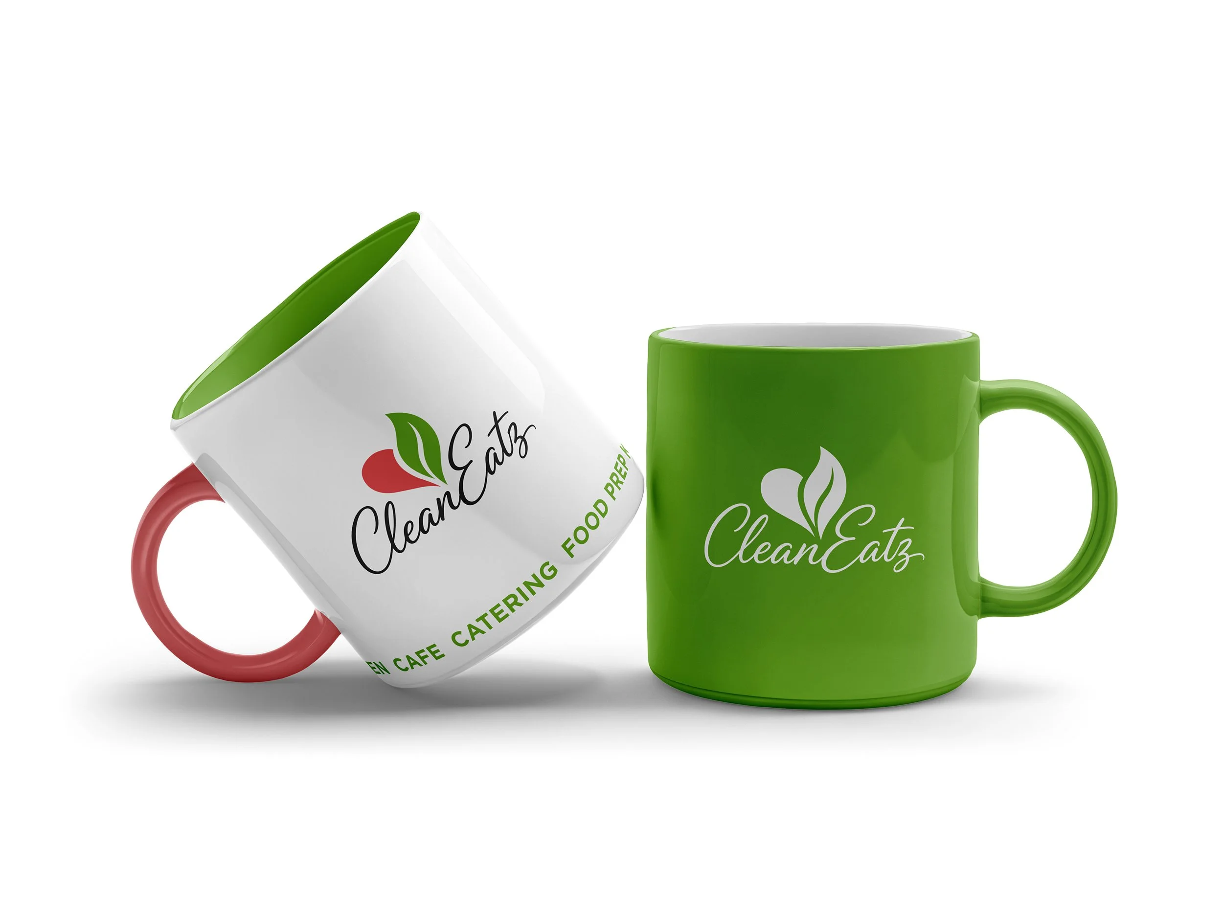 Two enamel coffee mugs, one with a white exterior and green interior and red handle, the other with a green exterior and handle, both with "CleanEat" logo and the different serves listed.