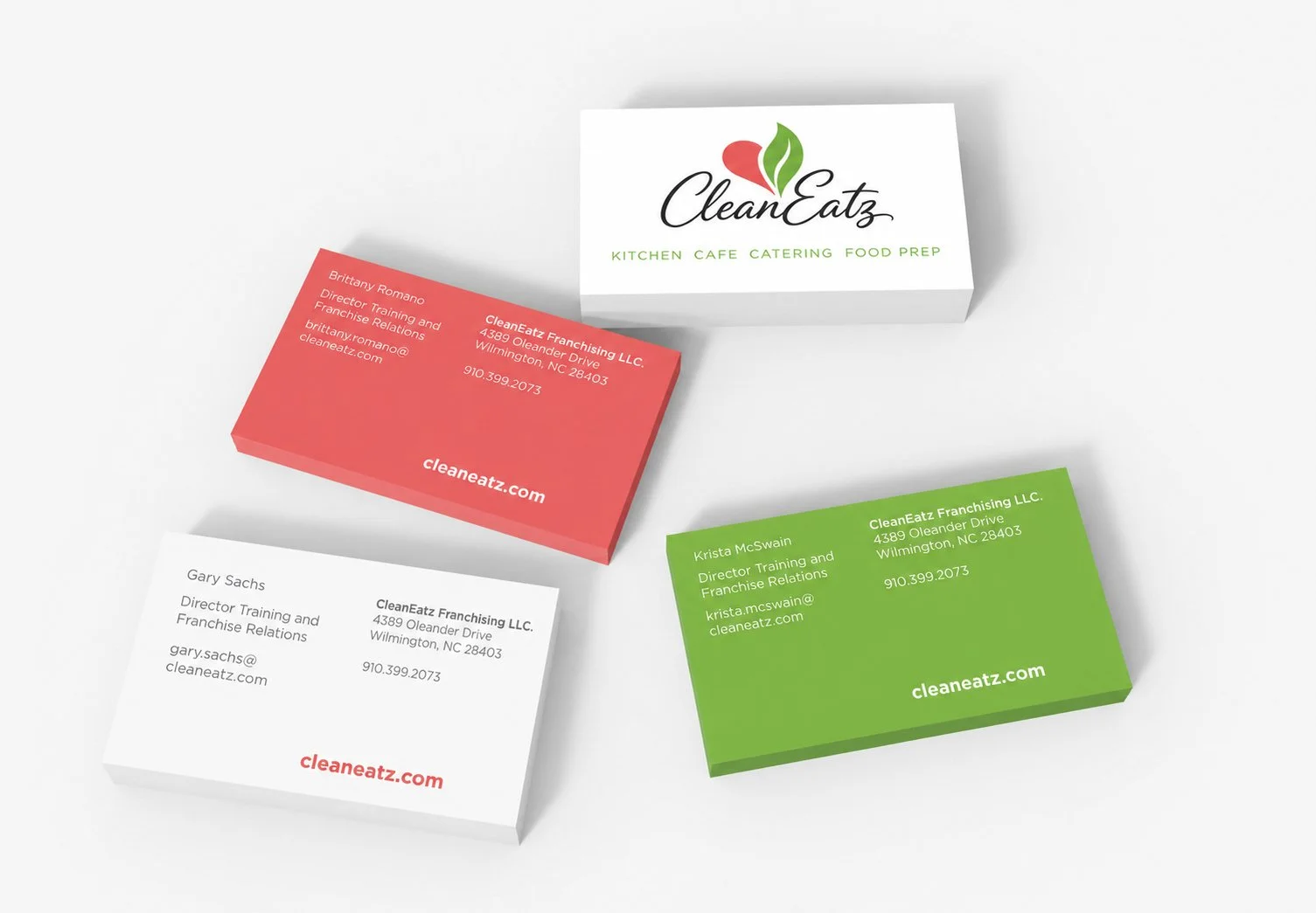 Business cards in several different colors, the back its white and reads  'CleanEatz' with a slogan 'Kitchen Cafe Catering Food Prep' on a white background. Other stack of business cards are white, green and strawberry red.