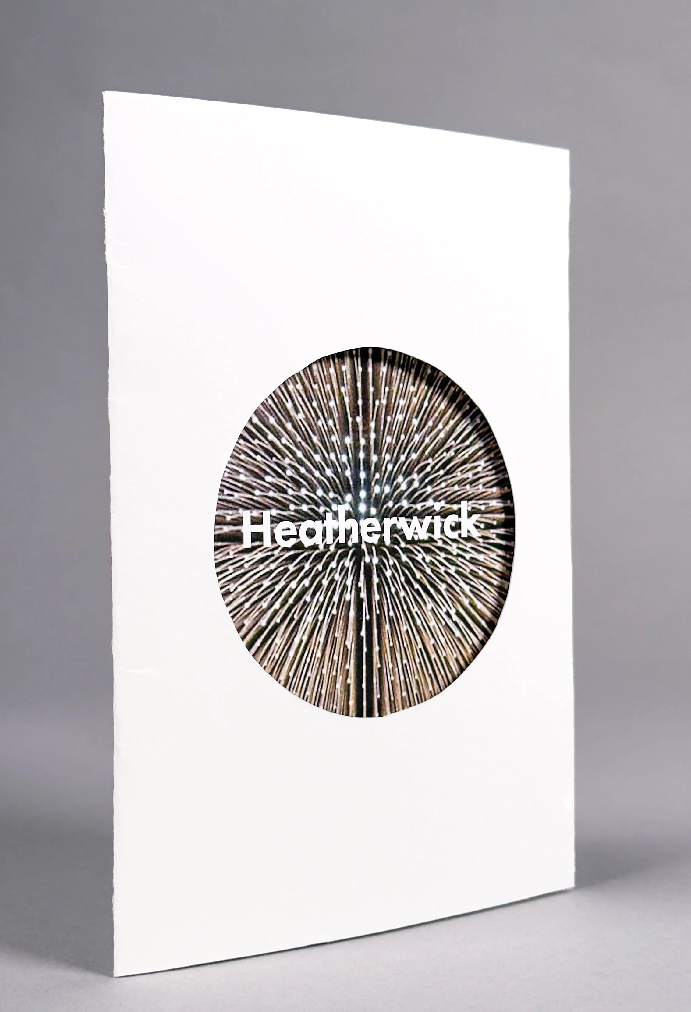 A white book with a circular design featuring radiating lines and the name 'Heatherwick' on the cover.