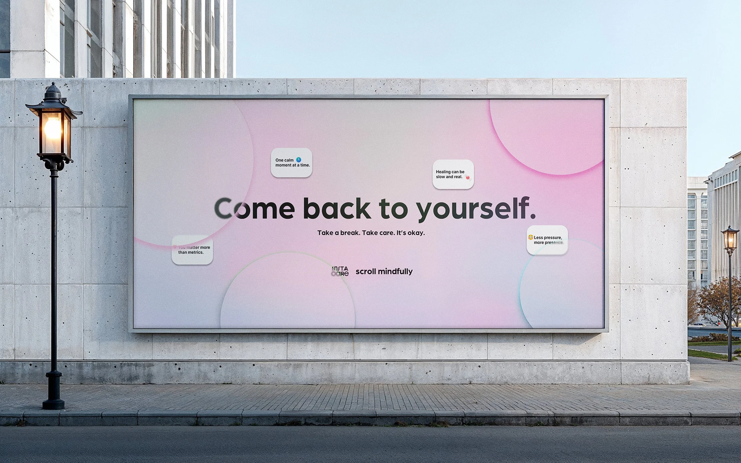 A large urban billboard displays a motivational bubbly message, 'Come back to yourself' with smaller quotes about mindfulness and self-care. The billboard is mounted on a concrete wall, with a street lamp and surrounding buildings in the background.