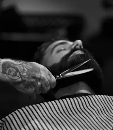 Barber trimming a customer’s beard at Wigram Barbers in The Landing Wigram