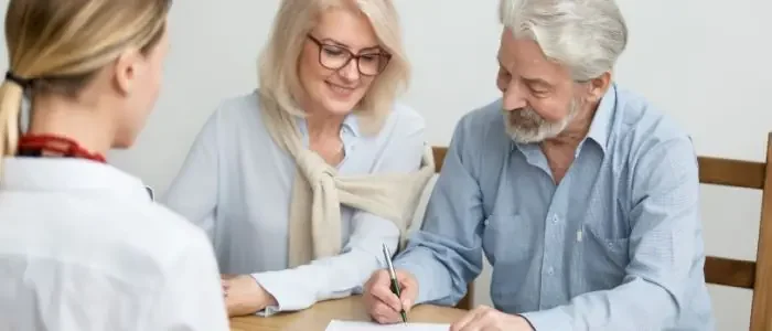 Couple signing documents during a wills and estate-planning consultation