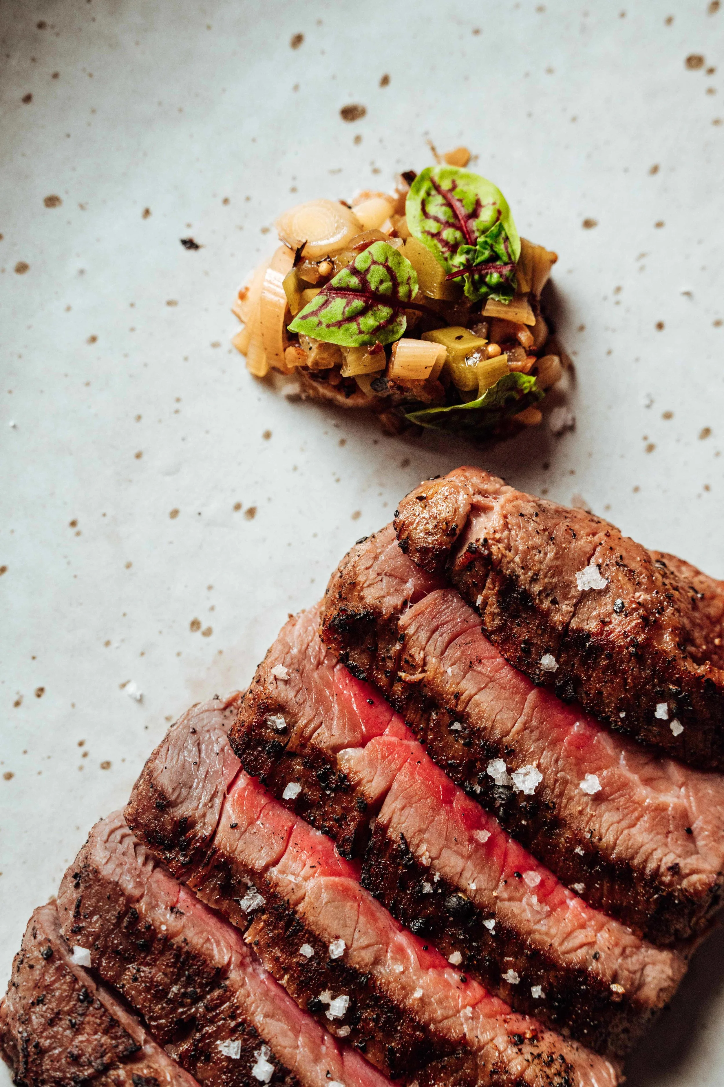 Slices of medium-rare grilled steak with salt crystals on top.