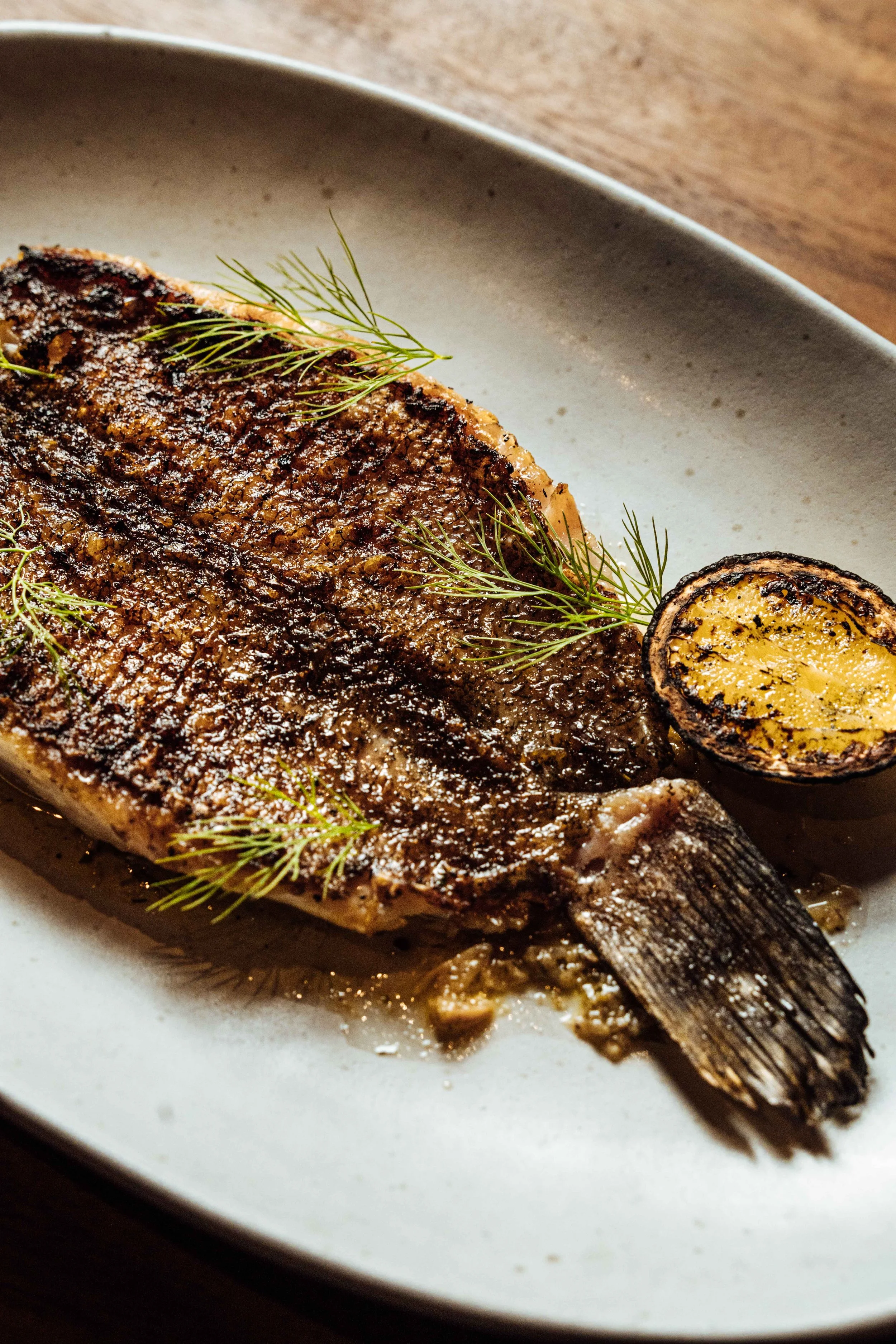 Grilled fish garnished with fresh herbs on a white plate.