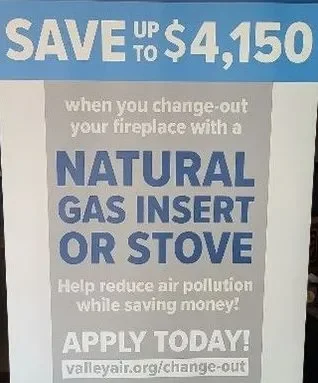 Sign promoting savings with natural gas insert or stove to reduce air pollution