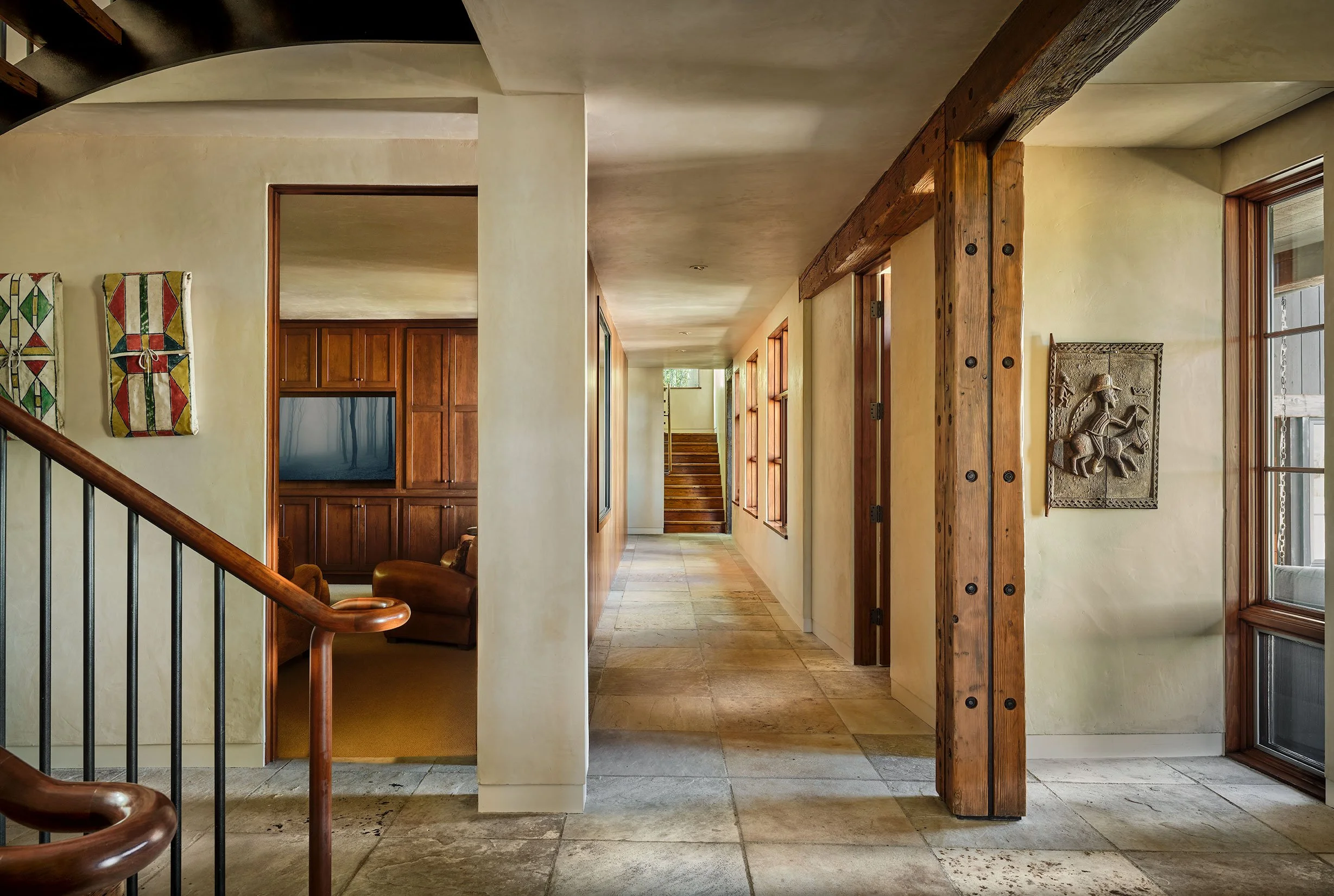 A hallway with wooden accents, a staircase, and artwork on the wall.