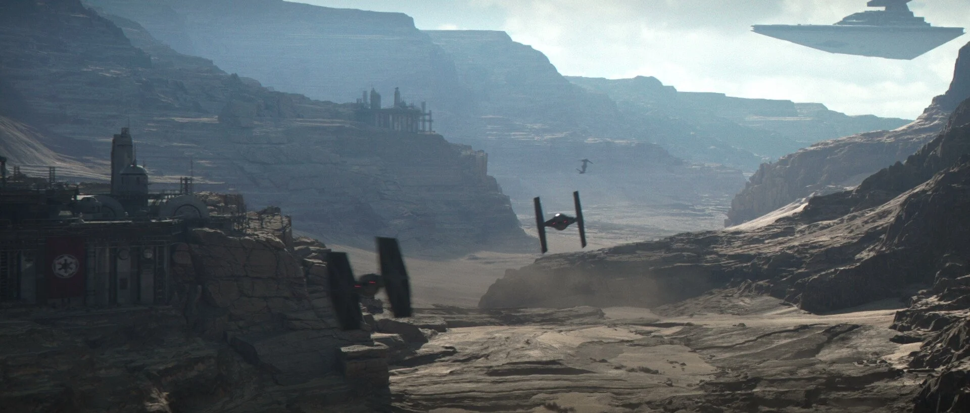 Spaceship flying over a rocky, canyon-like landscape with mountains in the background and a spaceship flying in the sky.