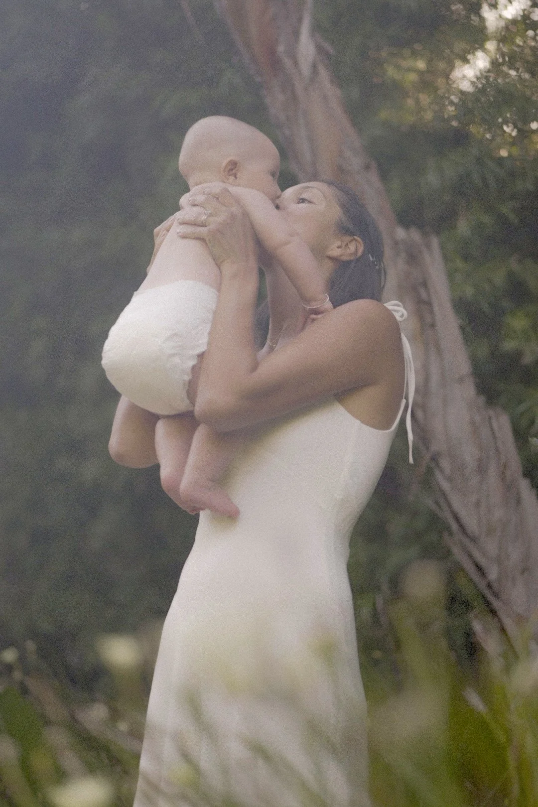 Mother lifting her baby overhead outdoors
